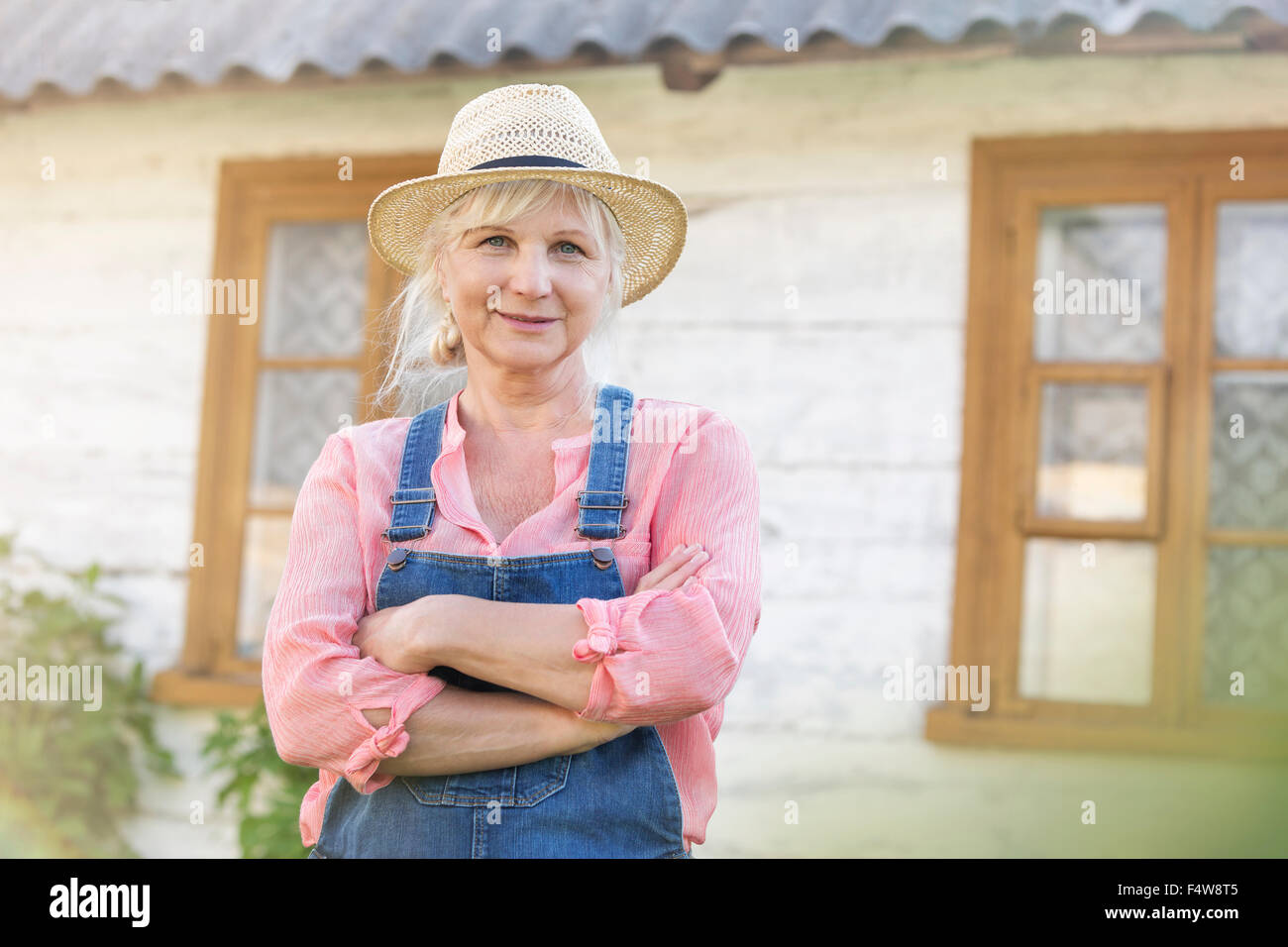 Porträt lächelnd Landwirt in Overalls und Strohhut außerhalb Bauernhaus Stockfoto