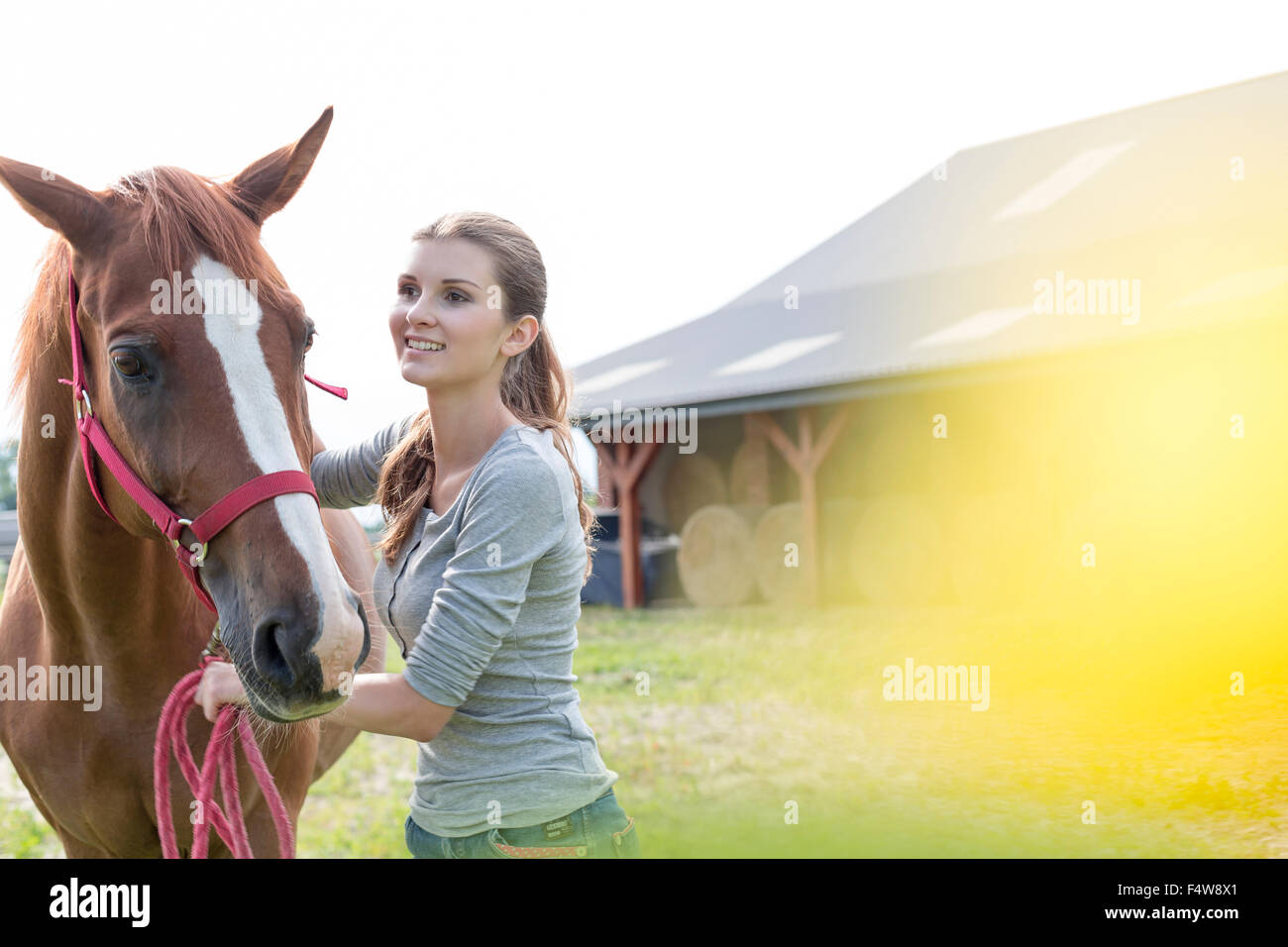 Lächelnde Frau mit Pferd außerhalb ländlichen Scheune Stockfoto