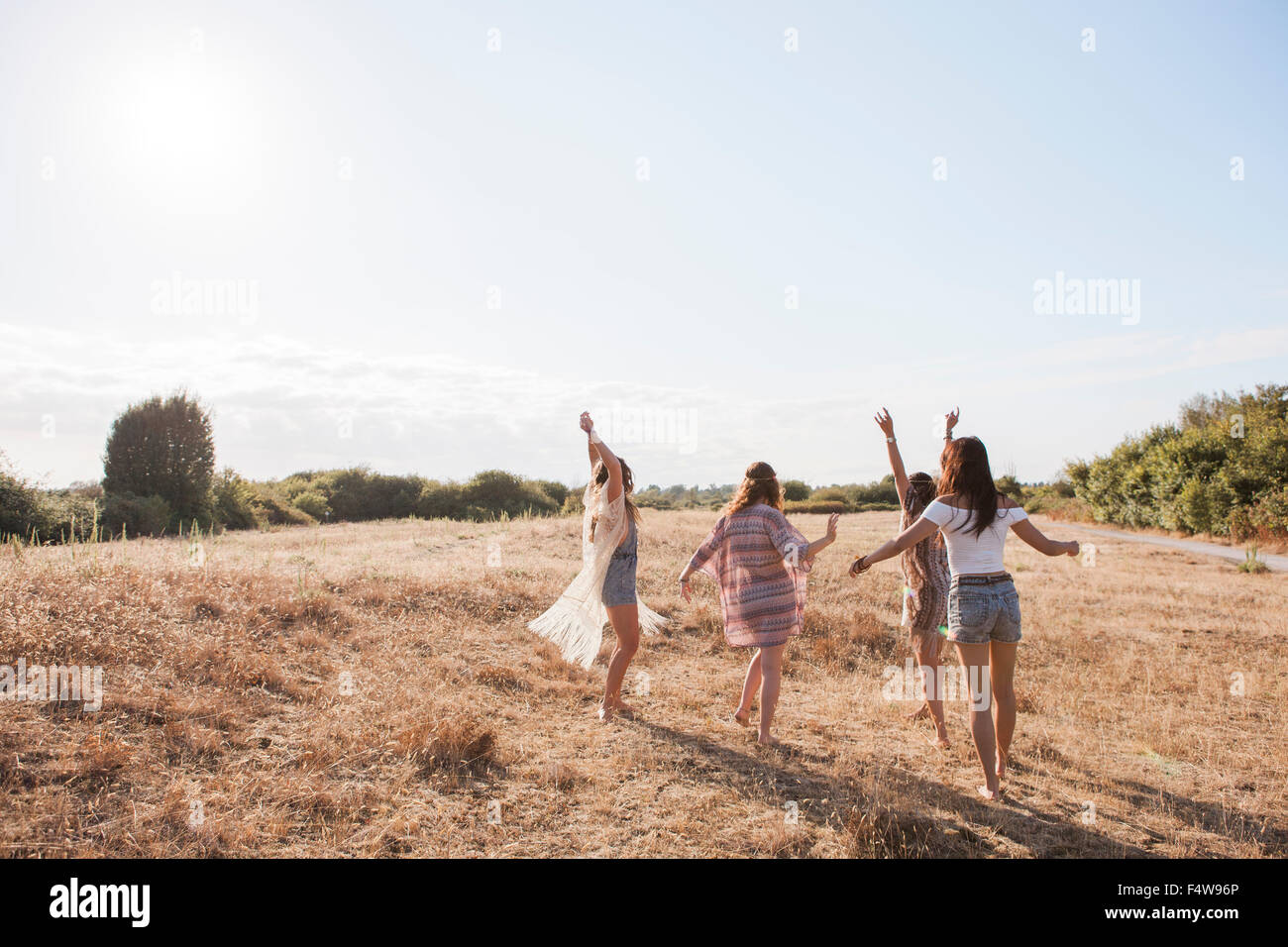 Unbeschwerte Boho Frauen tanzen auf sonnigen ländlichen Gebiet Stockfoto