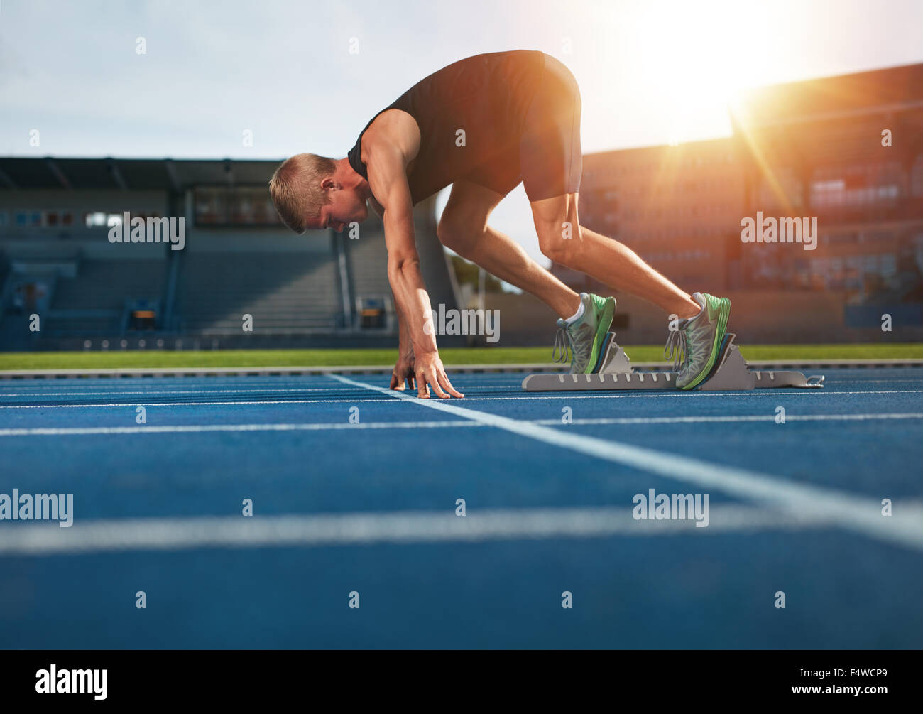 Junger Mann auf die Ausgangsposition für den Betrieb bereit. Männlicher Athlet in den Startlöchern auf sportliche Strecke ausgeführt werden soll. Stockfoto