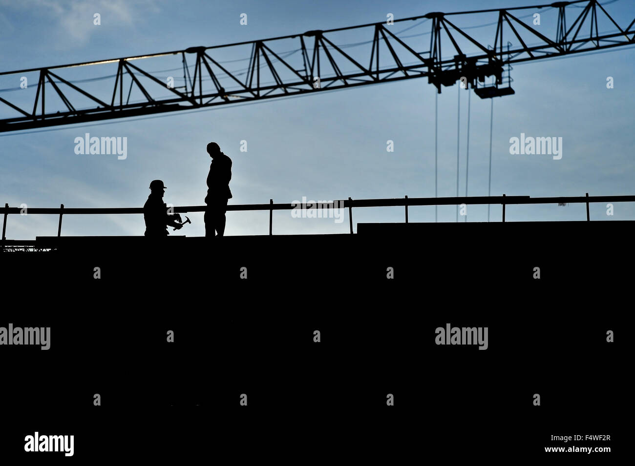 Bau Arbeiter Silhouetten auf einer Konstruktion mit blauen Himmel im Hintergrund Stockfoto