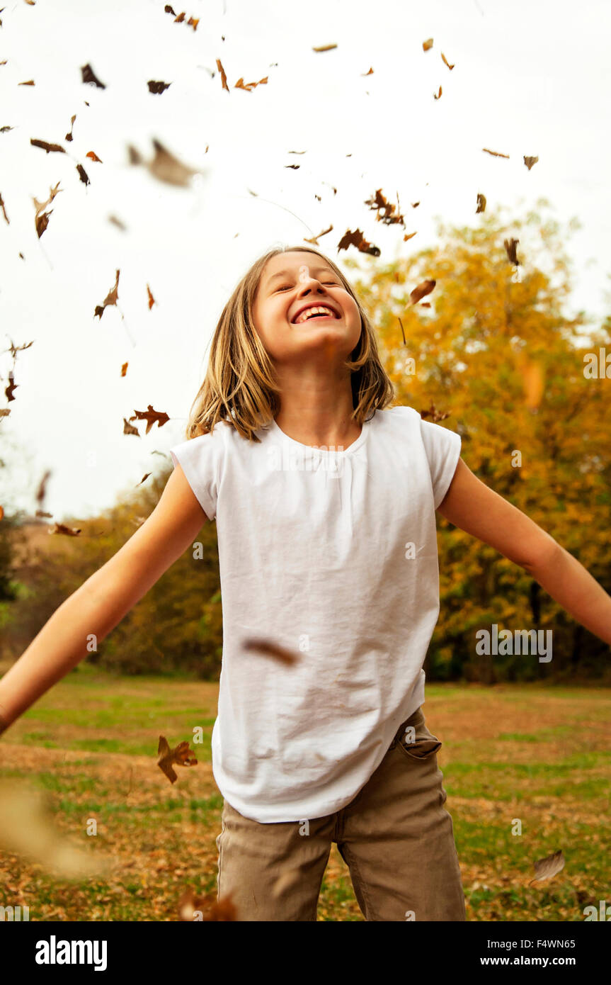 Mädchen stehen im Herbst fallendes Laub Stockfoto