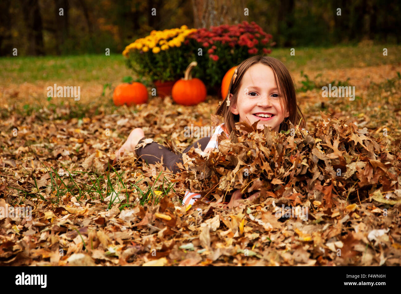 Mädchen spielen im Herbstlaub Stockfoto