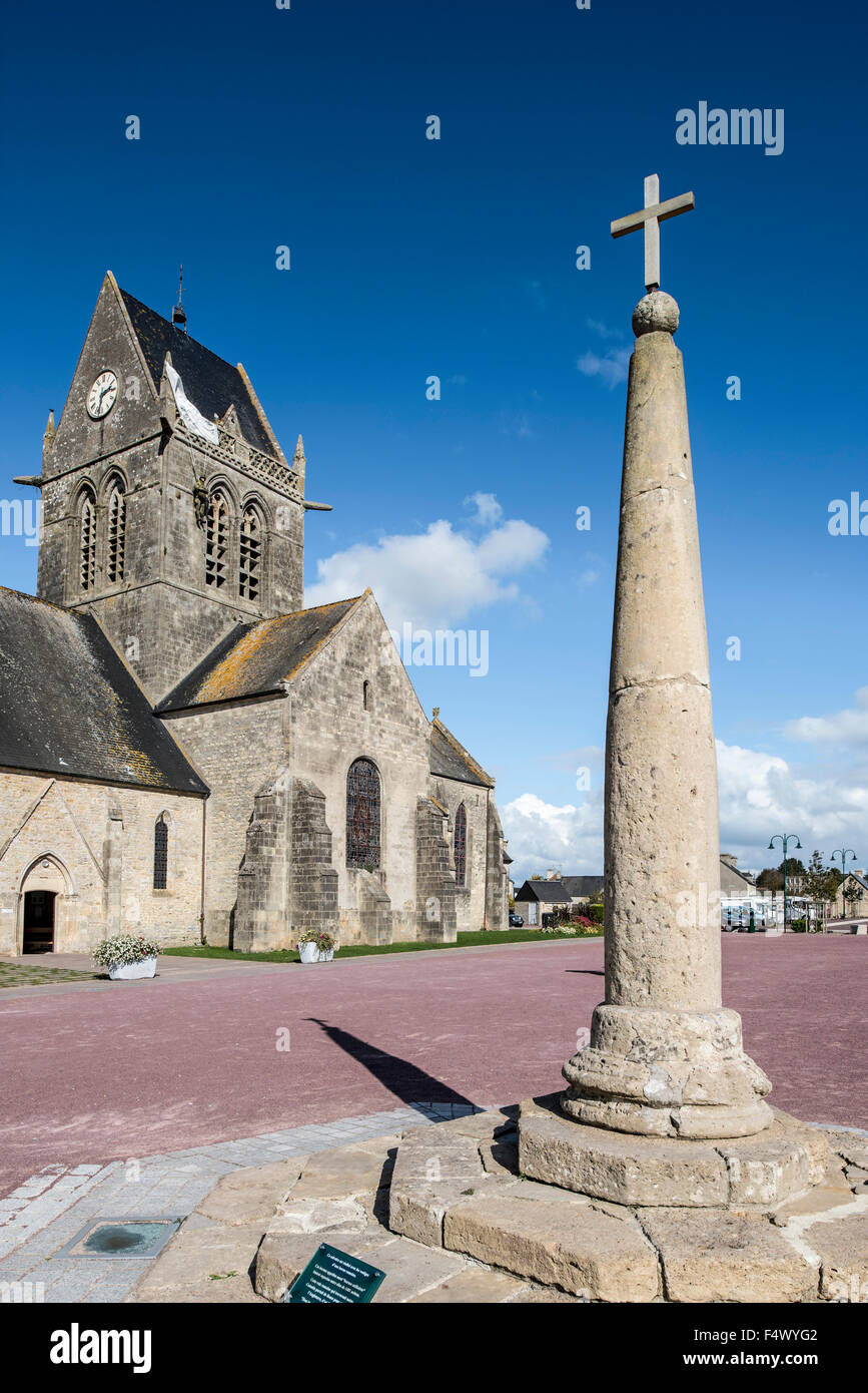Milliarium Stein platziert neben Römerstraßen und Sainte-Mère-Église Kirche mit Fallschirm Memorial, Normandie, Frankreich Stockfoto