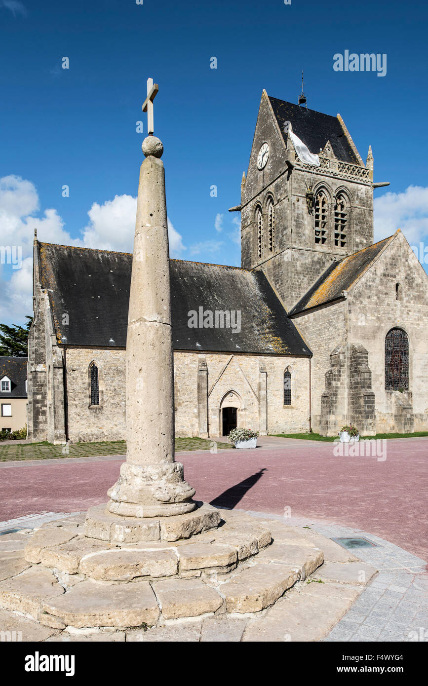 Milliarium Stein platziert neben Römerstraßen und Sainte-Mère-Église Kirche mit Fallschirm Memorial, Normandie, Frankreich Stockfoto
