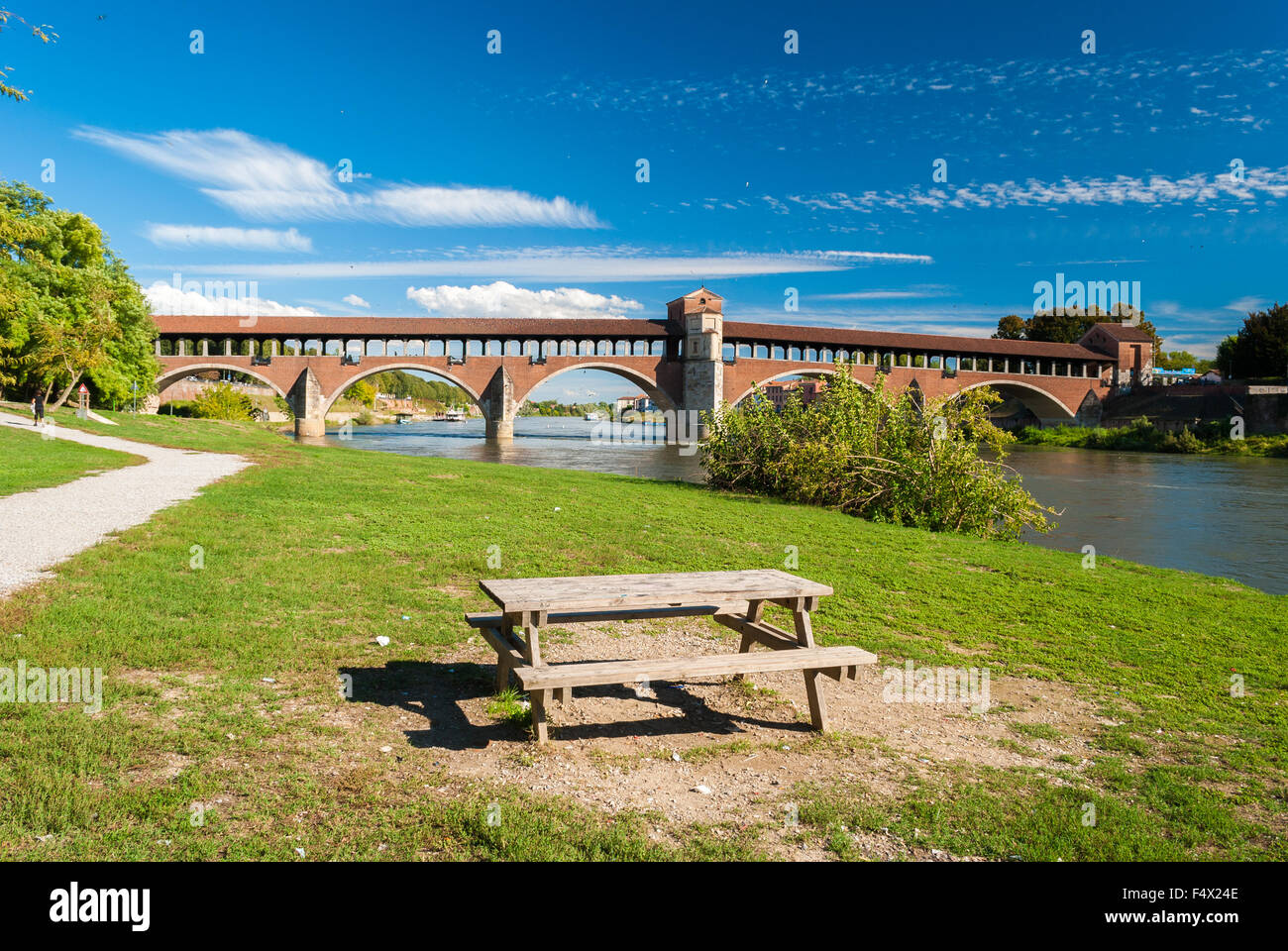 Tisch in der Nähe der Ufer des Flusses Ticino in Pavia; die "Ponte Coperto" im Hintergrund Stockfoto