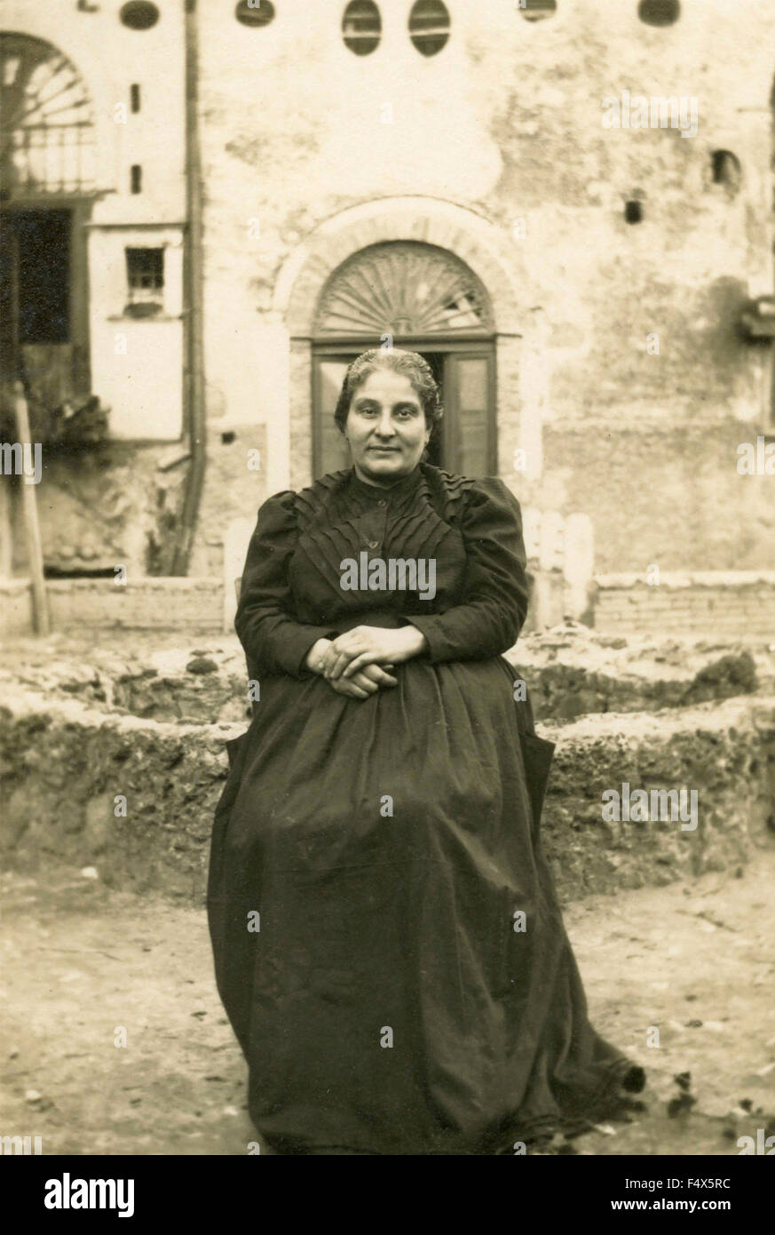 Eine ältere Frau mit einem großen schwarzen Kleid sitzen im Garten, Italien Stockfoto