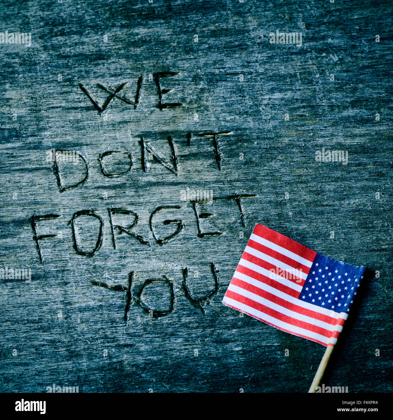 der Text, den wir nicht vergessen, dass Sie in einem alten hölzernen Oberfläche und eine Flagge der Vereinigten Staaten geschnitzt Stockfoto