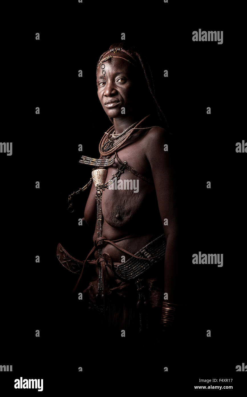 Eine Himba-Frau zeigt ihre traditionelle Kleidung und Schmuck. Stockfoto