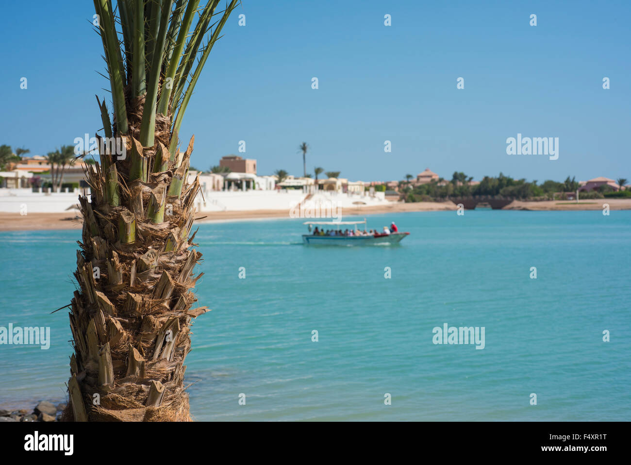 Wasser-Taxi voll von Menschen, die Reisen auf einer tropischen Lagune See mit Palme im Vordergrund Stockfoto