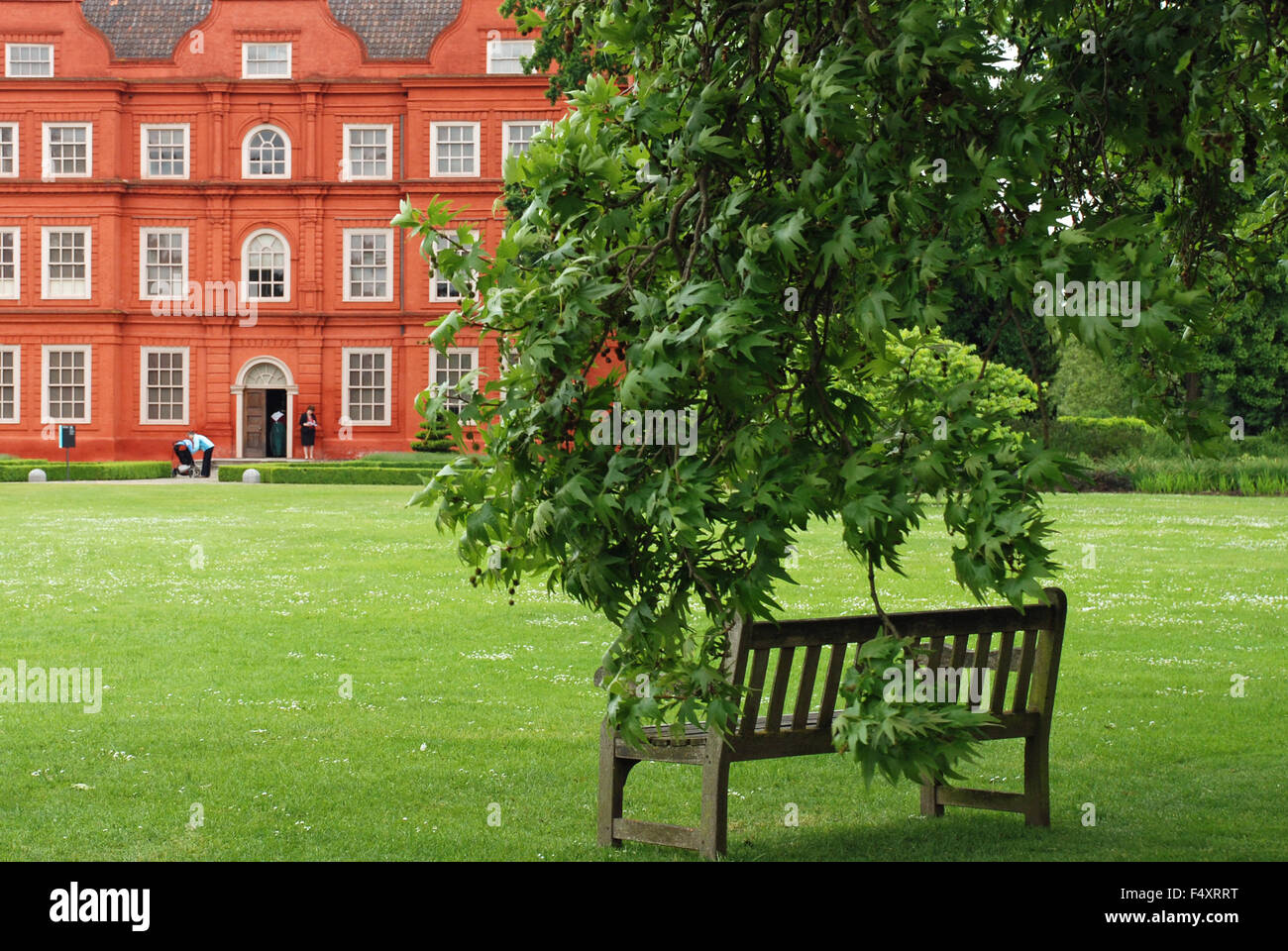 Gartenbank außerhalb Kew Palace verdeckt durch belaubte Äste in Kew Botanical Gardens, London, England Stockfoto