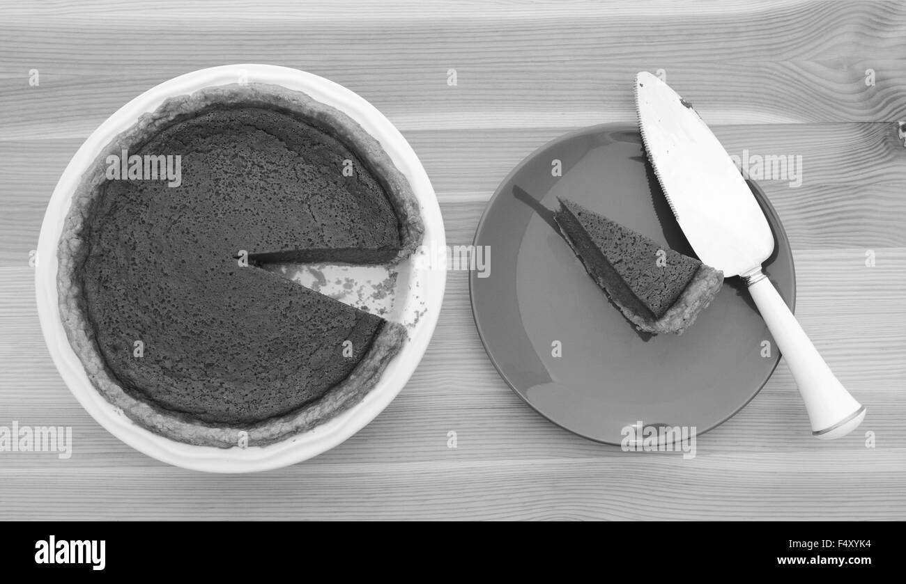 Verarbeitung von Slice einen Kürbiskuchen mit einem Tortenheber auf einem Teller - monochrome entnommen Stockfoto