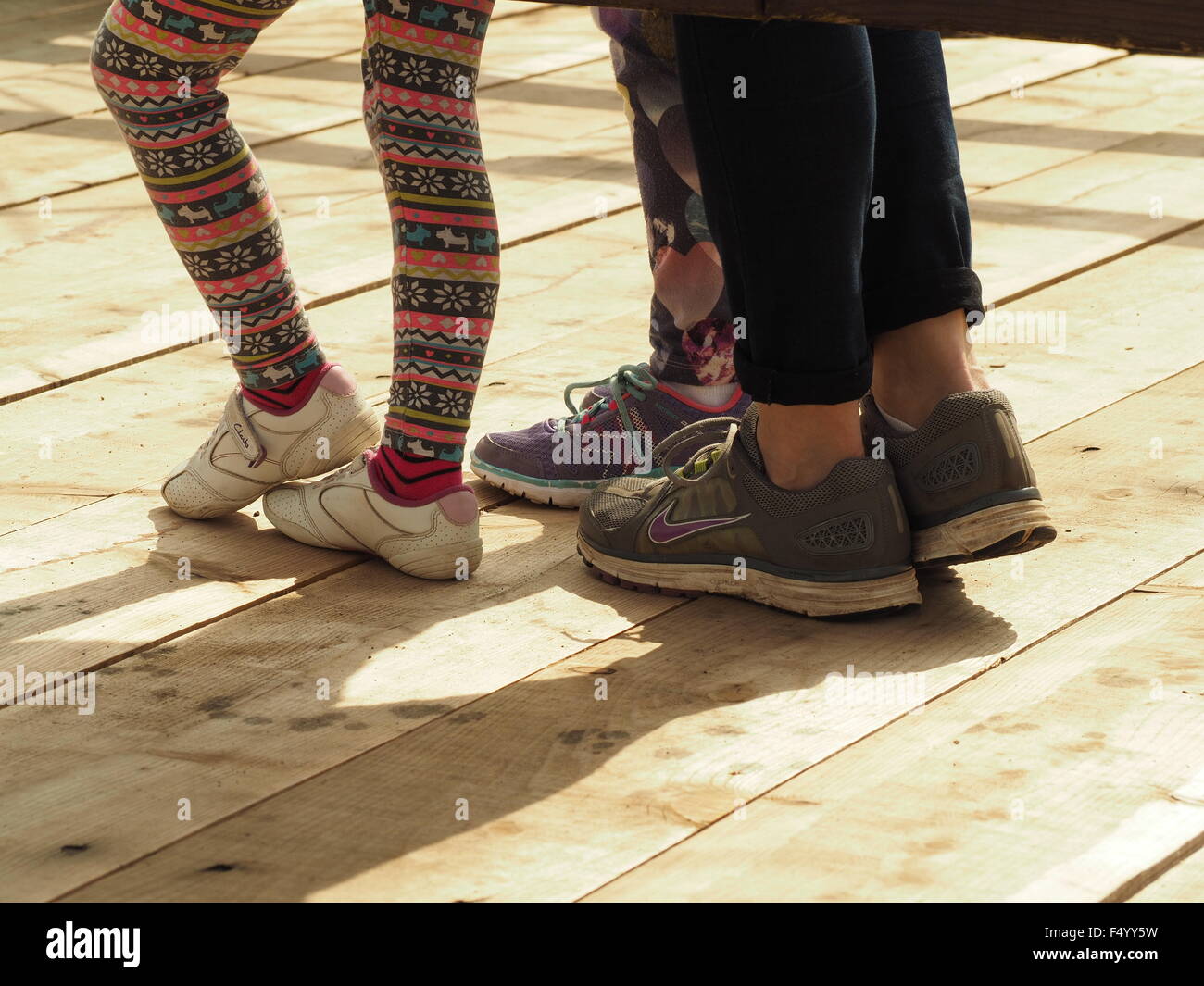 junge Menschen Beine mit Trainer Sneaker schicke Leggings und Jeggings in kecke Pose auf Terrasse mit Schatten Stockfoto