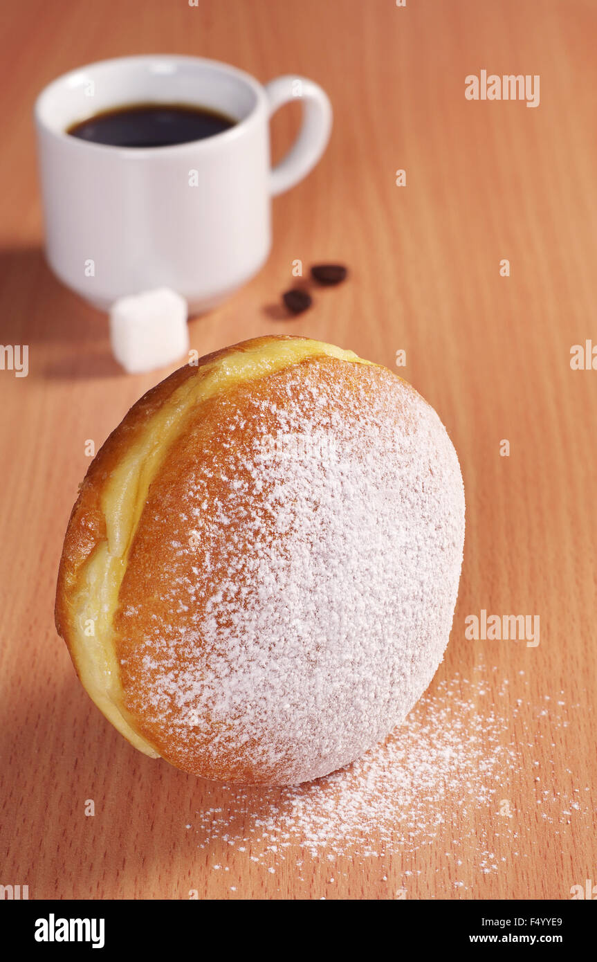 Berliner Krapfen mit Tasse heißen Kaffee am Schreibtisch Stockfoto