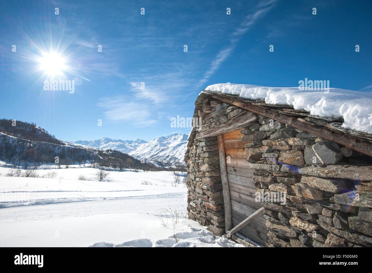 Entfernten alpine Hütte an einem Hang im Sonnenlicht mit Schnee bedeckt Stockfoto