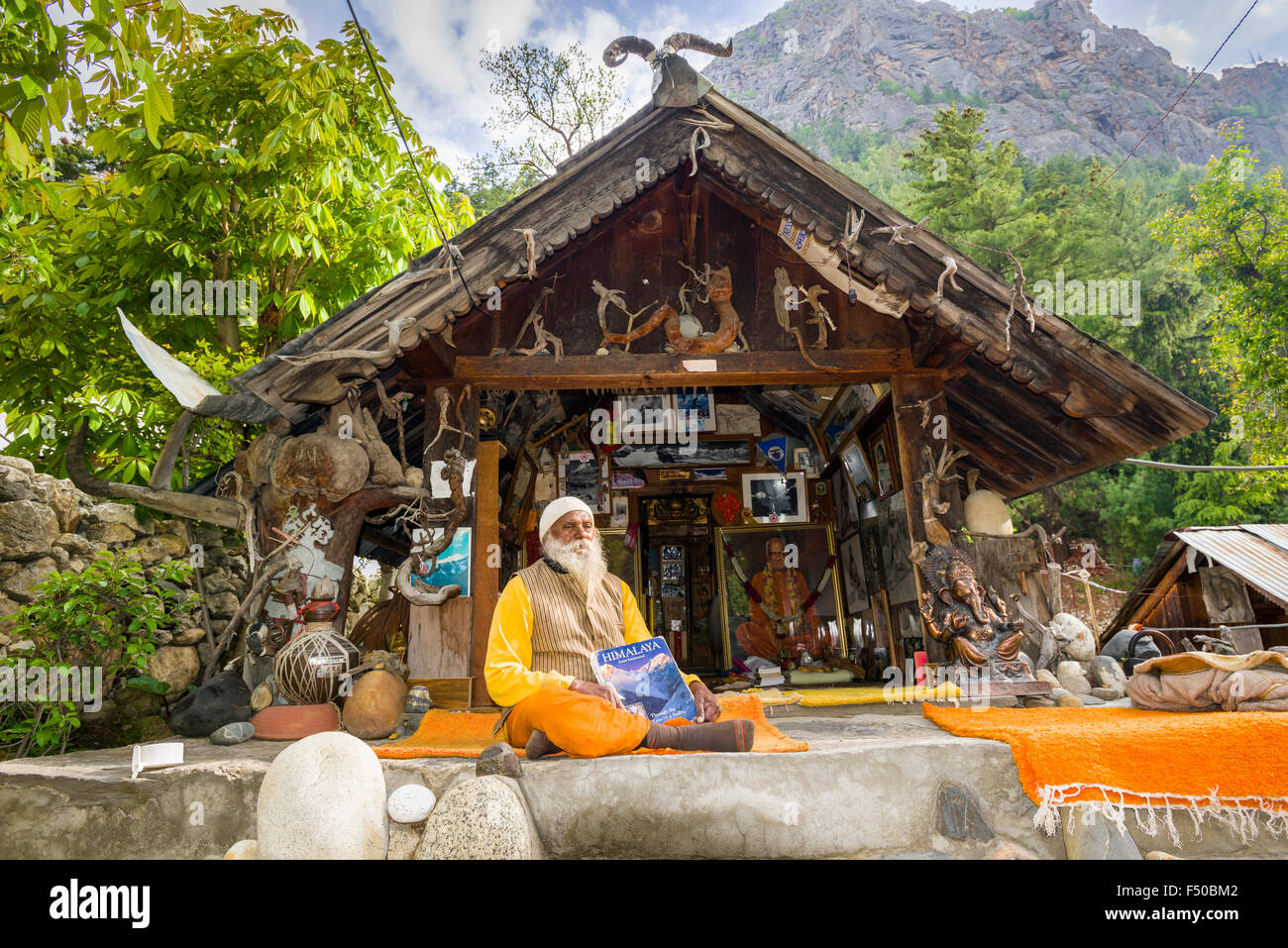 Swami sundaranand, einem berühmten Sadhu, Yogi und Fotograf, sitzt vor seinem Haus und seinem Buch anzeigen Stockfoto