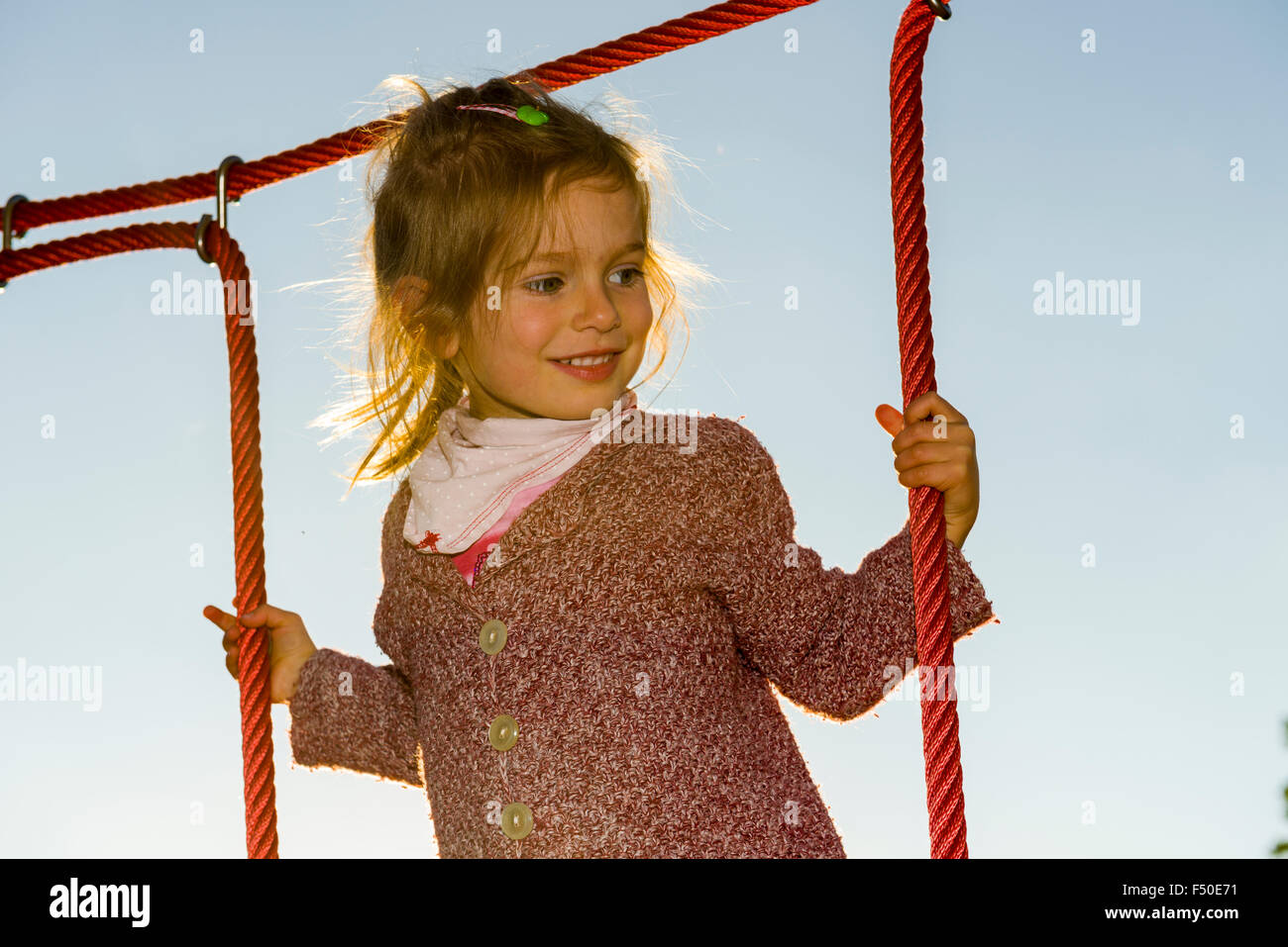 Ein drei Jahre altes Mädchen ist Klettern ein Seil Gerüst Stockfoto
