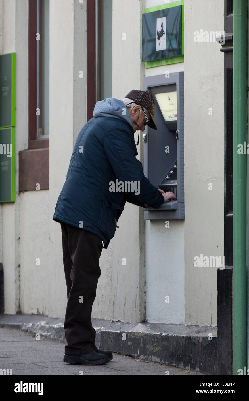 Ein Rentner-Rentner zieht Scheckeinlösung verwendet einen Lloyds Bank Geldautomaten. Stockfoto