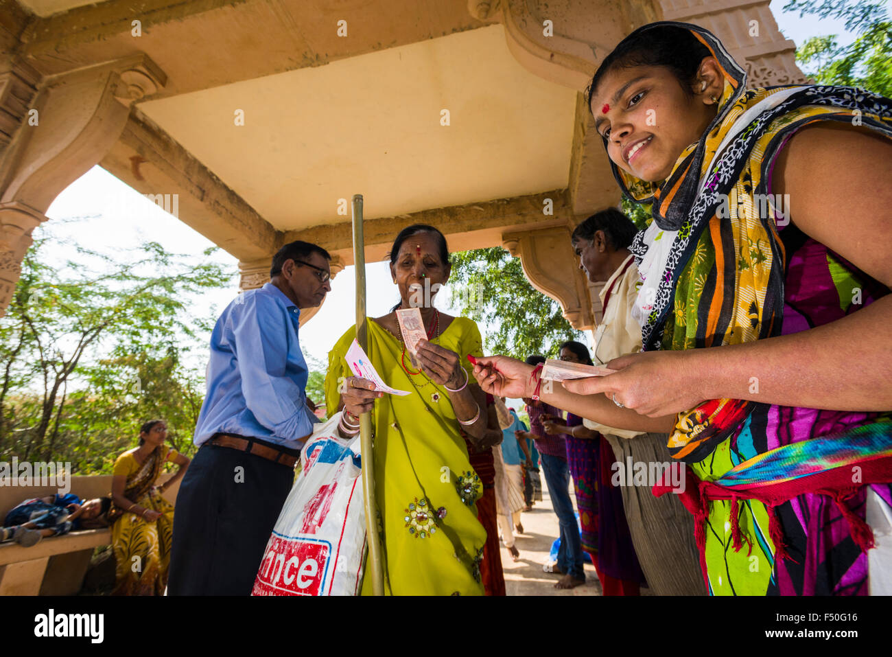 Eine reiche Familie bietet 10 indischen Rupien zu jedem der tausenden von Jain Pilger, die zu Fuß die 3.500 Schritte zu shatrunj Stockfoto