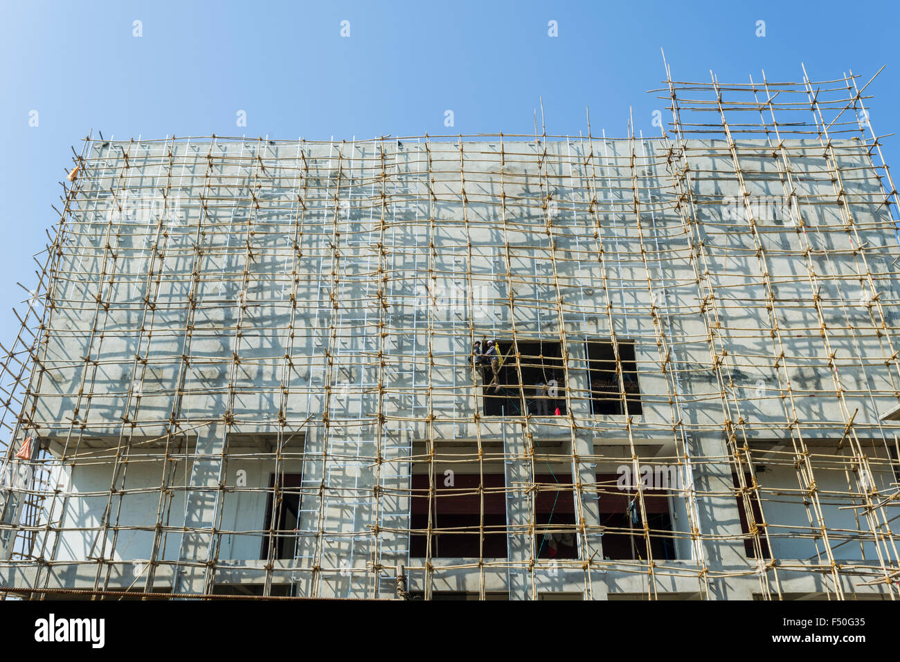 Eine Baustelle eines neuen Betongebäude mit einem Bambus Gerüst befestigt Stockfoto