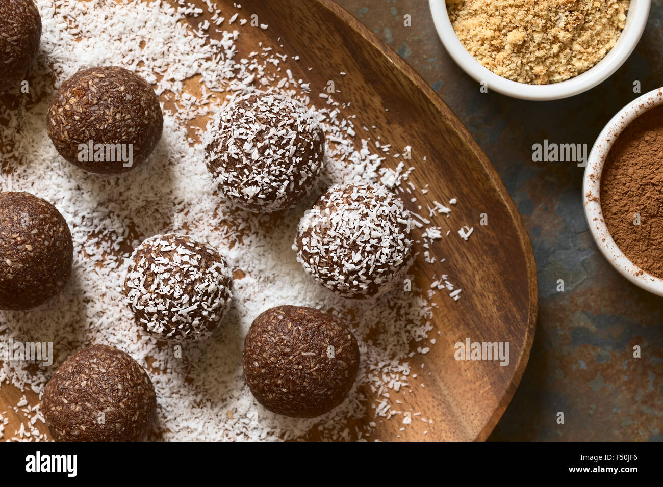 Kokos Rumkugeln Zutaten (Kakaopulver, Boden Cookies) auf der Seite mit Kokosraspeln auf Holzplatte, bedeckt Stockfoto