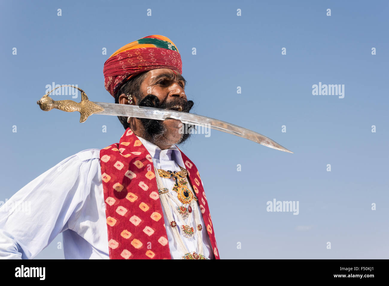 Vijai kumar Modi, ein rajput mit einer 1,50 Meter langen schwarzen Schnurrbart, posiert mit einem Schwert zwischen seinen Zähnen Stockfoto