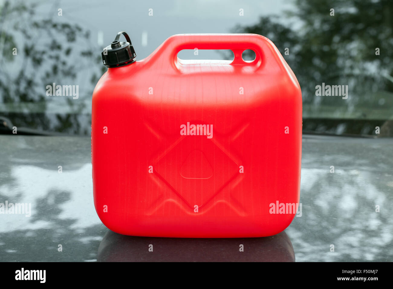 Neue rote Kunststoff-Kanister steht auf eine Motorhaube Stockfoto