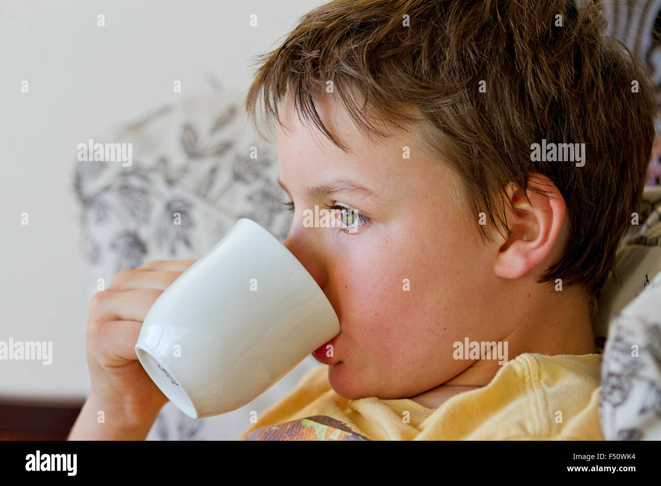 Ein zehn Jahre alter Junge bei einem heißen Getränk Stockfoto