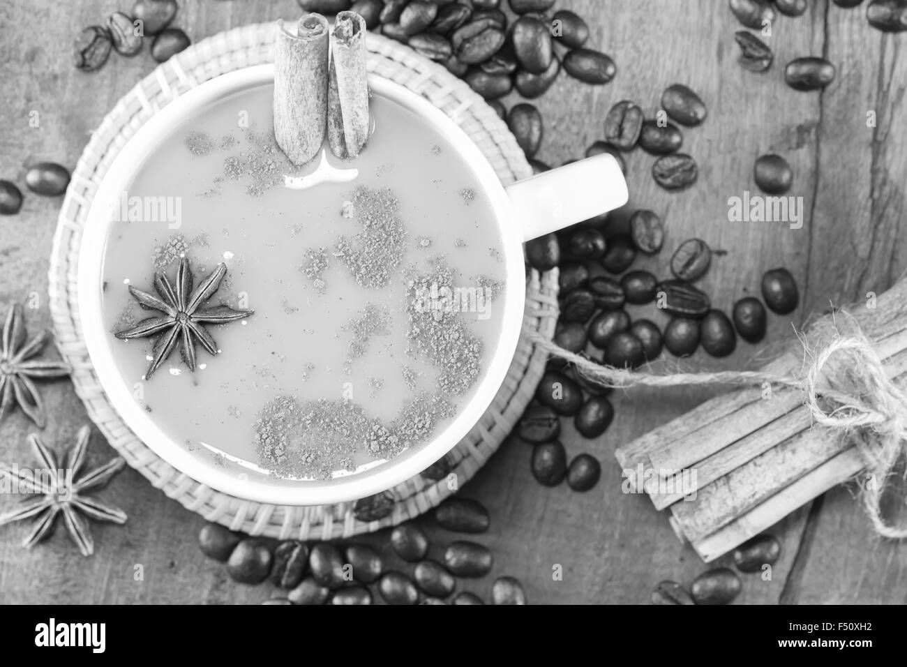 Kaffee in der Tasse mit Kaffeebohnen und Zimt klebt auf Holz Hintergrund auf schwarz und weiß, selektiven Fokus Stockfoto