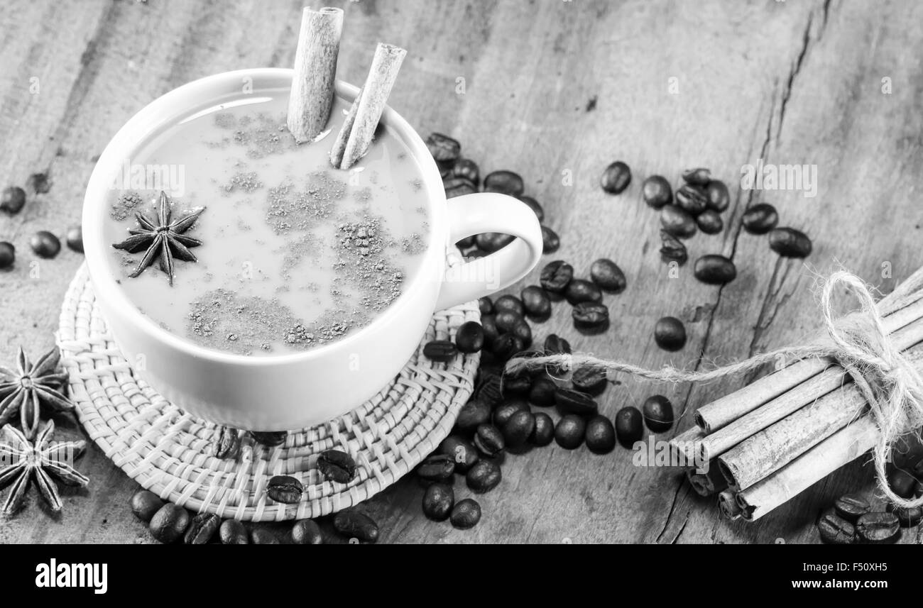 Kaffee in der Tasse mit Kaffeebohnen und Zimt klebt auf Holz Hintergrund auf schwarz und weiß, selektiven Fokus Stockfoto
