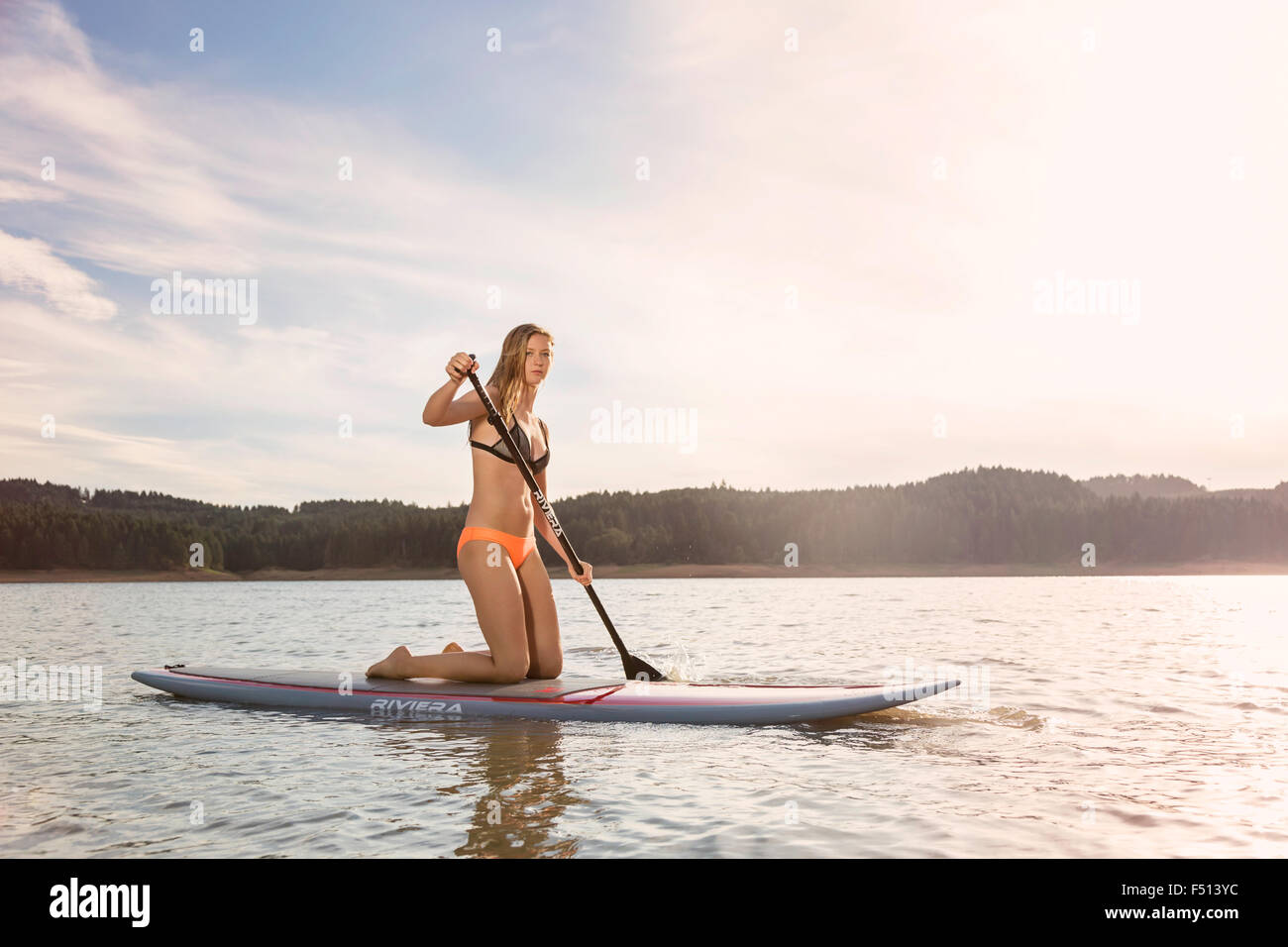 Schöne sportliche Frau Paddle boarding auf einem See in der Sonne Stockfoto