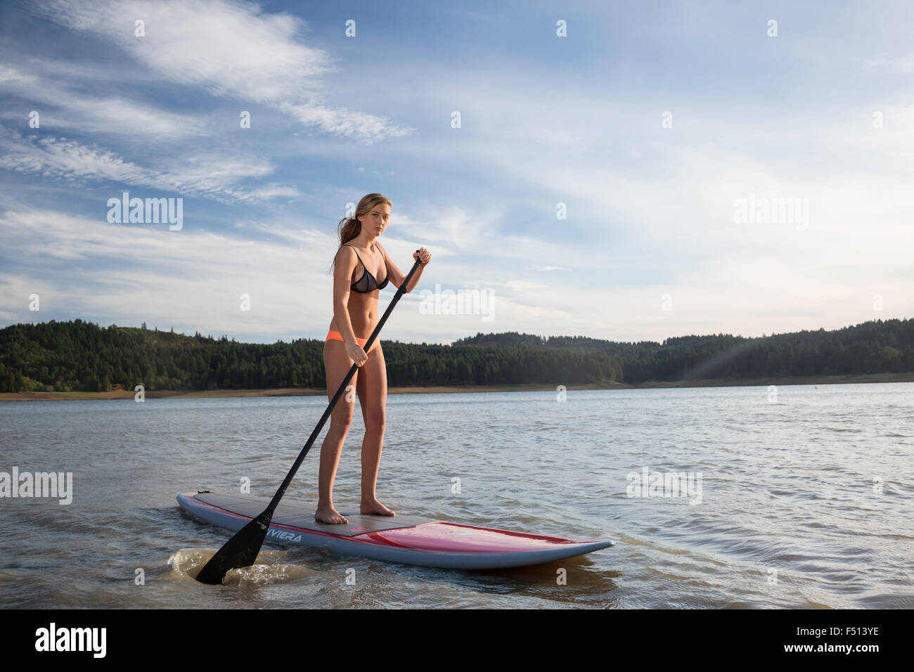 Schöne sportliche Frau Paddle boarding auf einem See in der Sonne Stockfoto