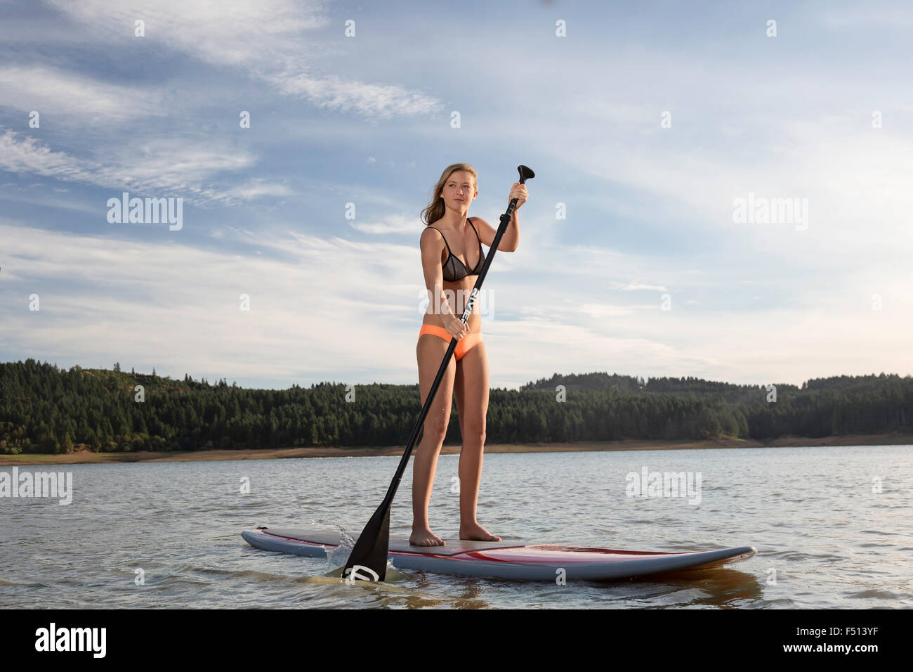 Schöne sportliche Frau Paddle boarding auf einem See in der Sonne Stockfoto