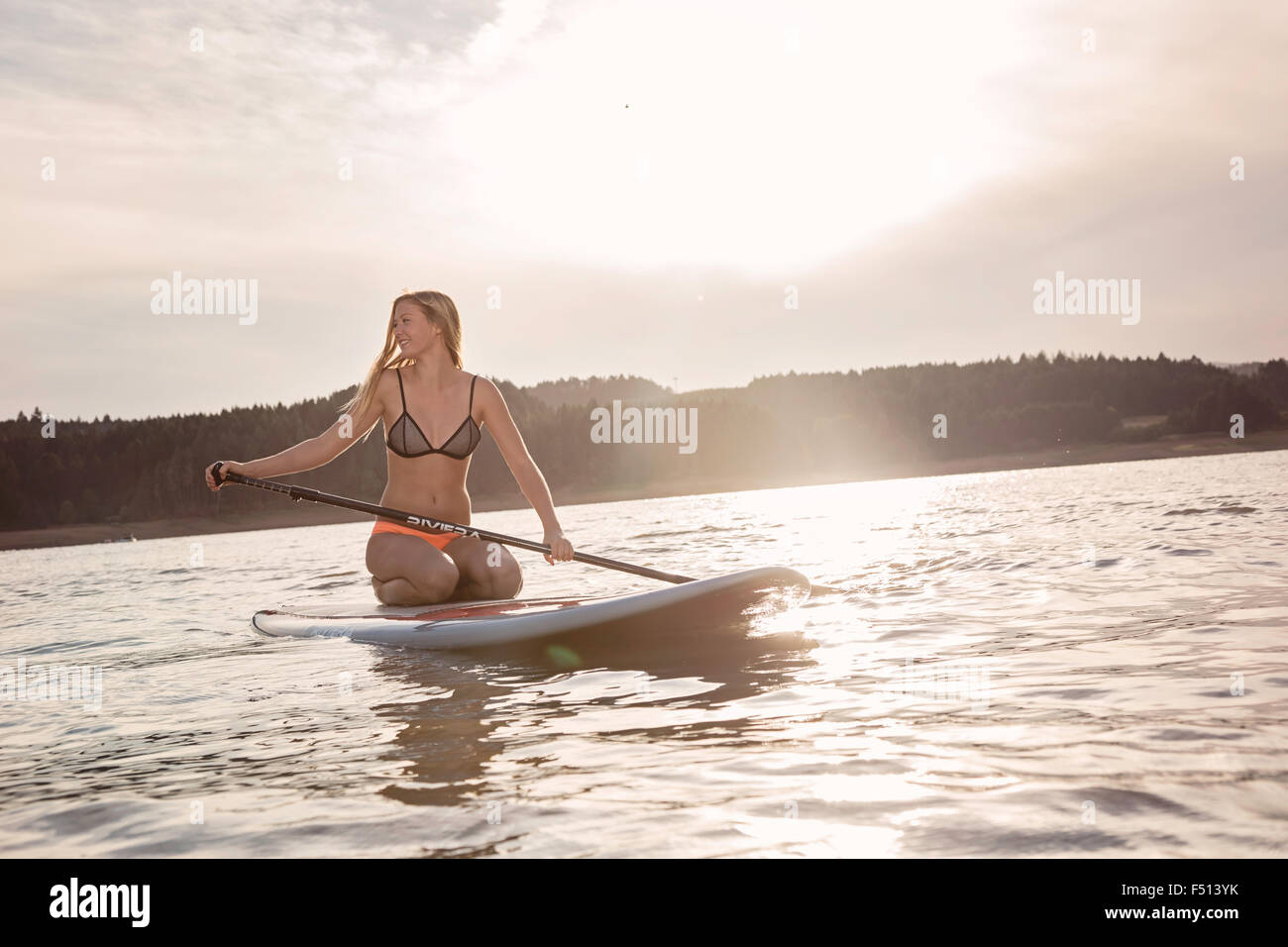 Schöne sportliche Frau Paddle boarding auf einem See in der Sonne Stockfoto