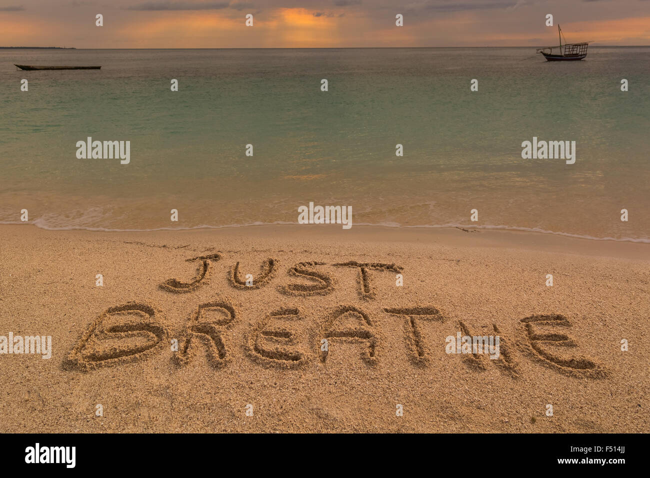 Auf dem Bild einen Strand bei Sonnenuntergang mit den Worten auf dem Sand "einfach atmen Sie". Stockfoto