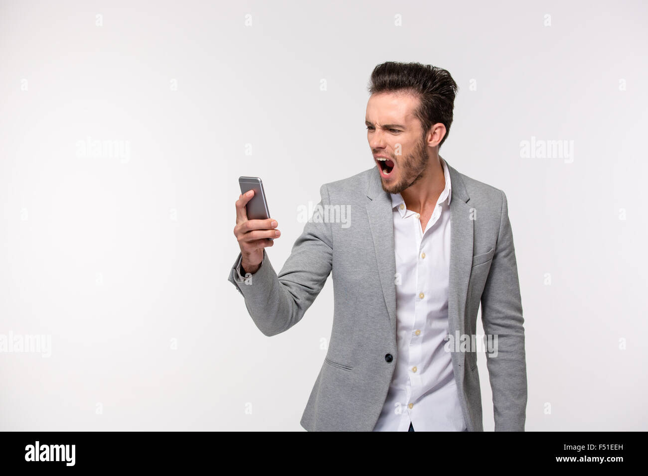 Porträt eines jungen Geschäftsmann schreiend auf Smartphone isoliert auf weißem Hintergrund Stockfoto