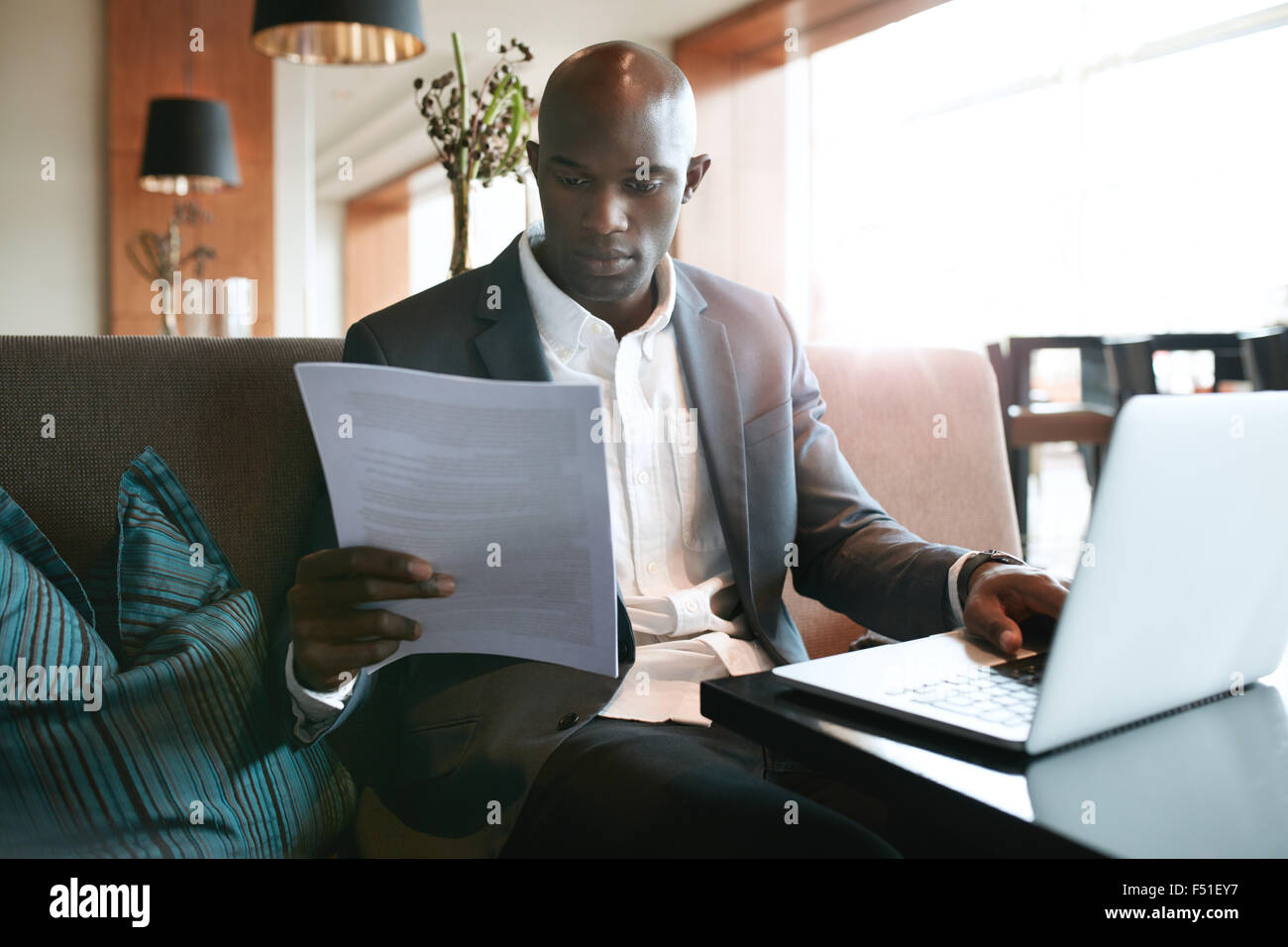 Bild der junge Geschäftsmann ein Hotel Café Lesen eines Dokuments während der Arbeit am Laptop sitzt. Bereitet sich auf ein paar Stockfoto