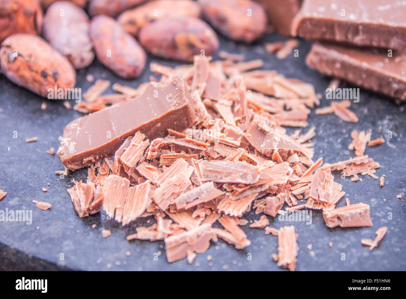Ein Haufen geriebener Schokolade vor Kakaobohnen und Milchschokolade Stockfoto