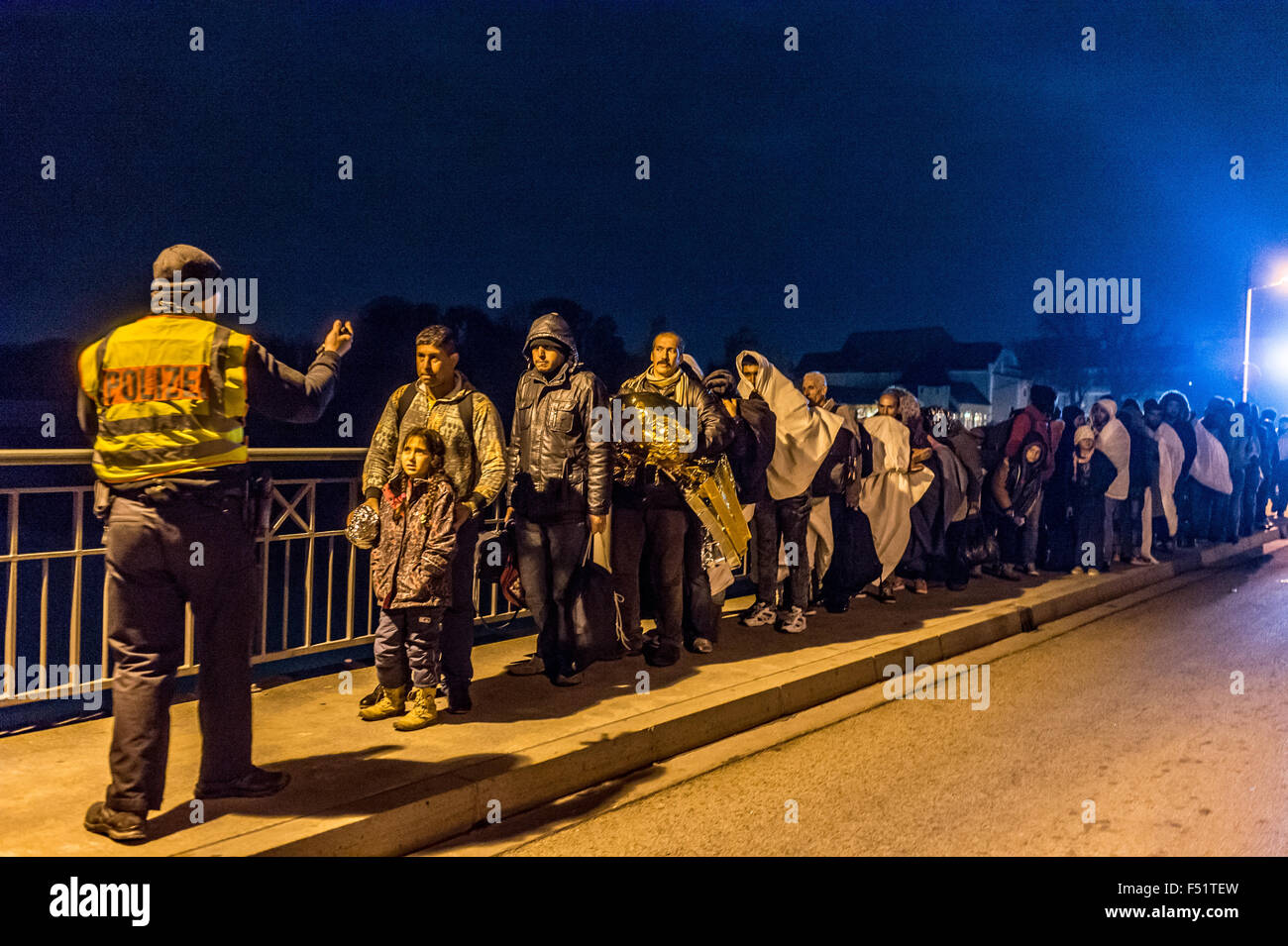 Passau, Deutschland. 25. Oktober 2015. Ein Polizist Colleccts eine Gruppe von Flüchtlingen auf Innbruecke Brücke an der österreichisch-deutschen Grenze zwischen Simbach bin Inn in Deutschland und Braunau in Österreich, 25. Oktober 2015. Die große Zahl der Flüchtlinge an der Grenze zwischen Österreich und Bayern ist für die deutsche Polizei zunehmend Probleme. Foto: ARMIN WEIGEL/DPA/Alamy Live-Nachrichten Stockfoto