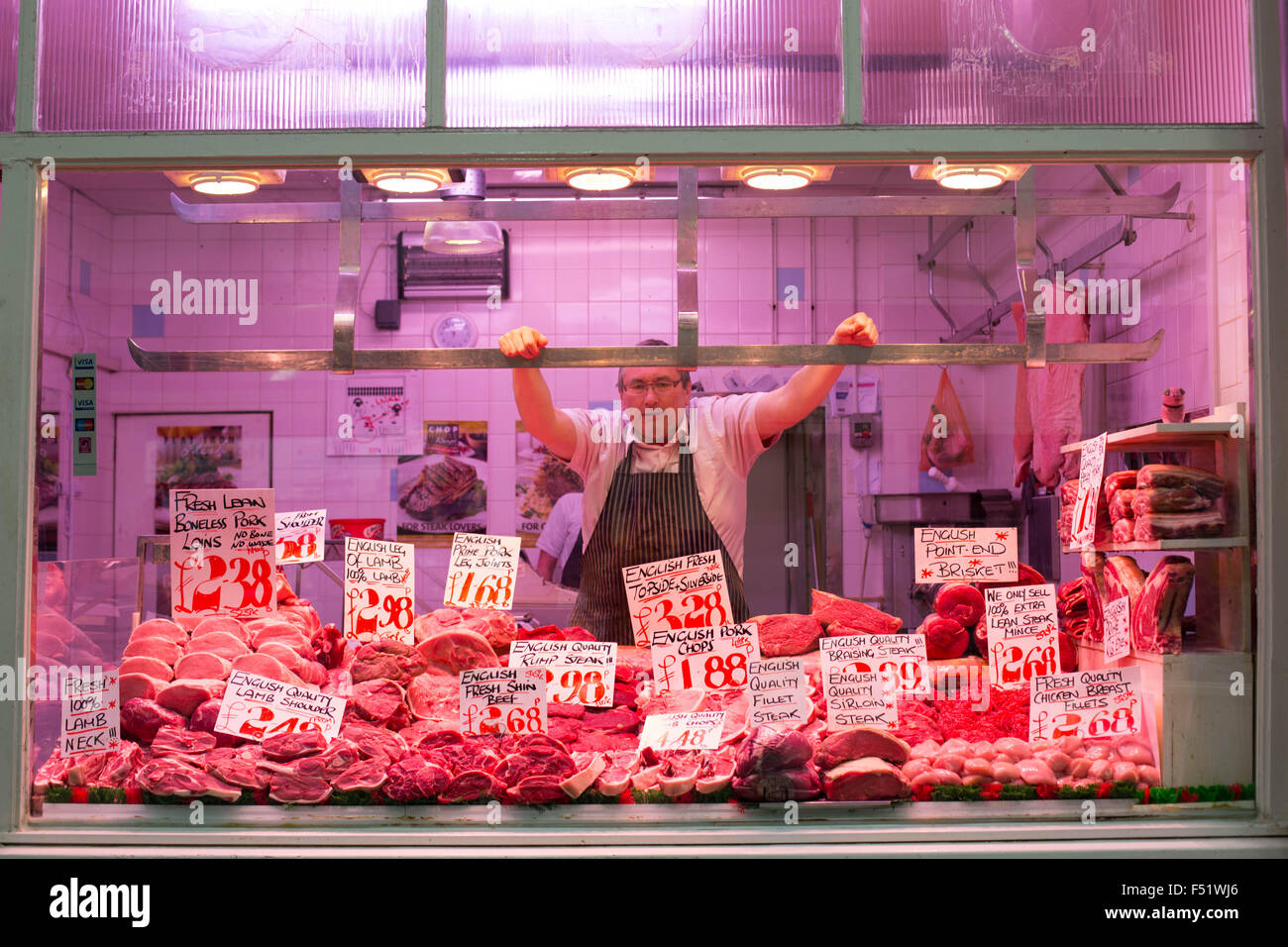 Ein Metzger in seinem Stall in Leeds Kirkgate Market in West Yorkshire, Großbritannien.  Es ist der größte überdachte Markt in Europa. Stockfoto
