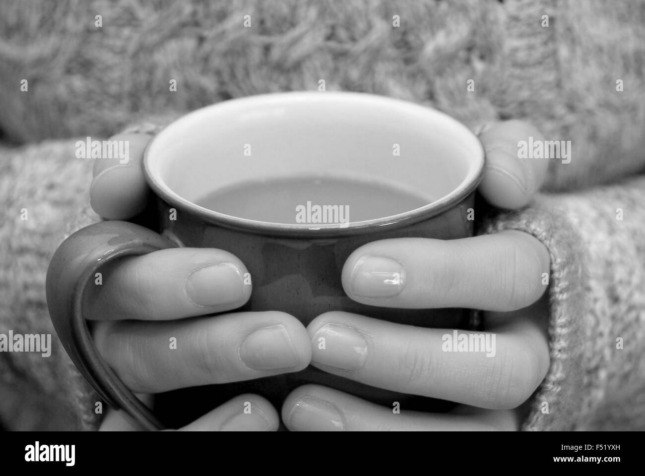 Zwei Hände halten warm, hält eine heiße Tasse Tee oder Kaffee - monochrome Verarbeitung Stockfoto