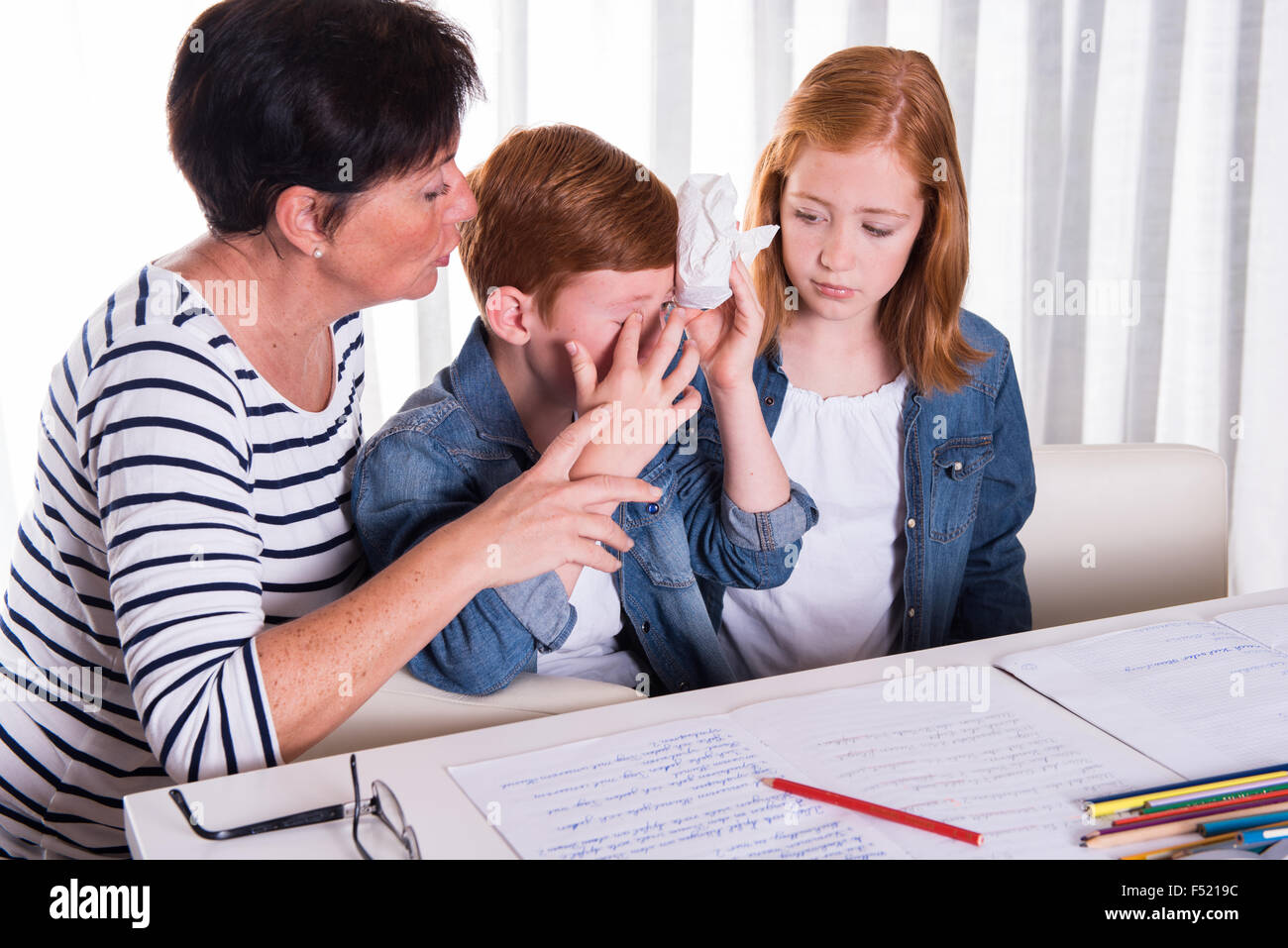 kleiner Junge bekommt von Mutter und Schwester getröstet. Stockfoto