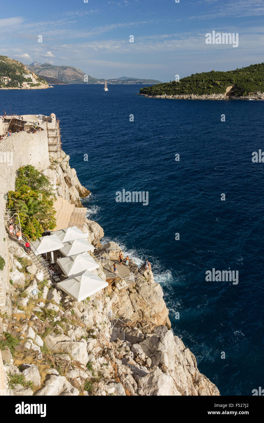 Malerische Aussicht auf ein Café auf einem Felsen außerhalb der Stadtmauern und die Insel Lokrum bei Dubrovnik, Kroatien. Stockfoto