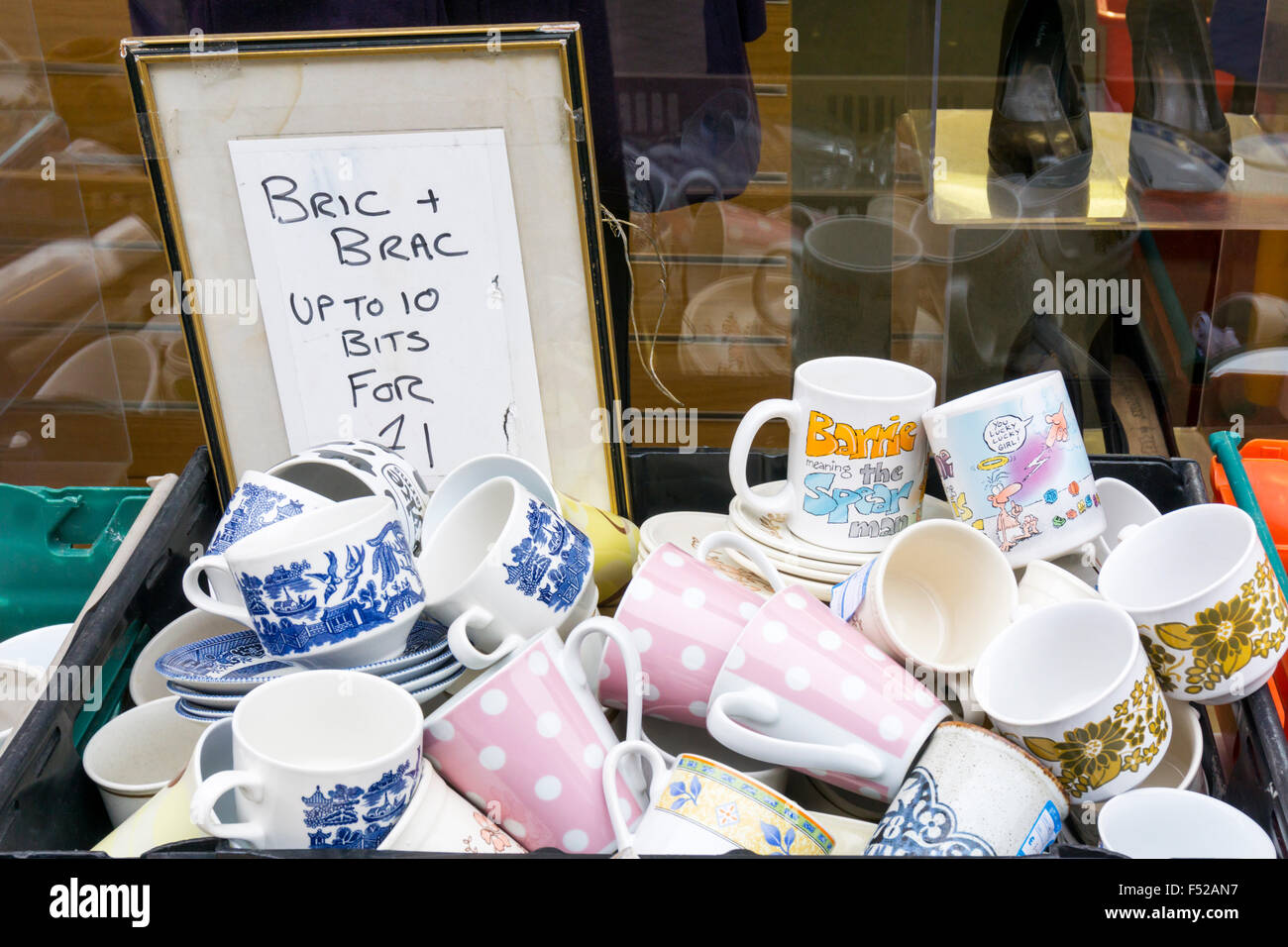 Eine Schachtel mit gebrauchten Geschirr Becher und Tassen für den Verkauf außerhalb einer Bric ein Brac-Shop. Stockfoto