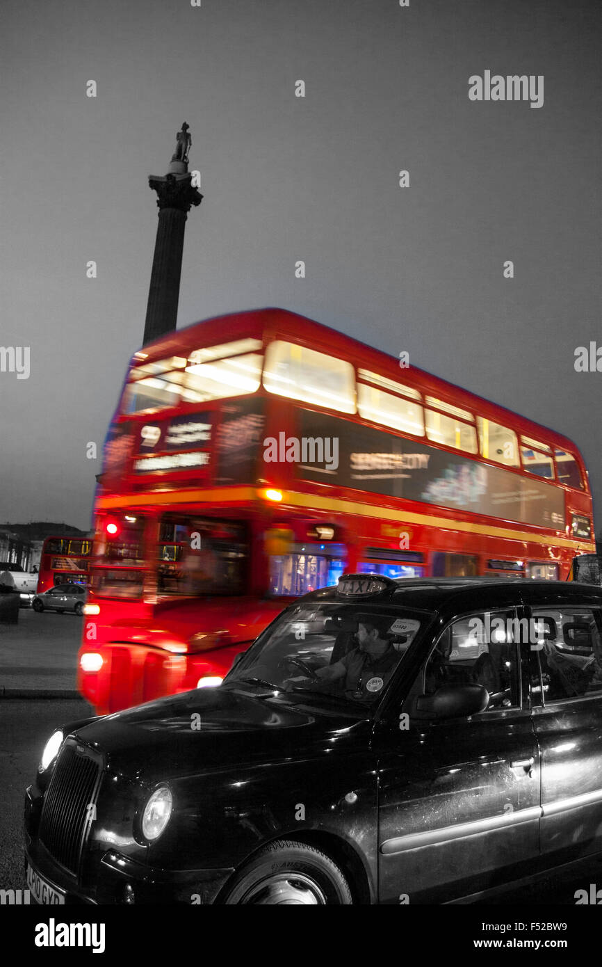 Trafalgar Square traditionelle rote Routemaster Bus und schwarzes Taxi Taxi vorbei Nelson Säule in der Nacht London England UK schwarz und Stockfoto