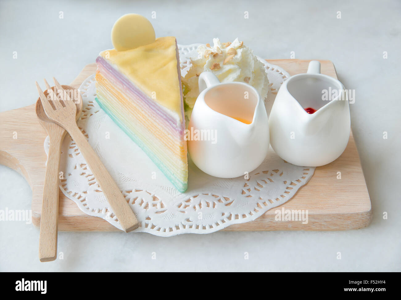 Regenbogen Crêpe Kuchen mit Sauce auf Holzplatte Stockfoto