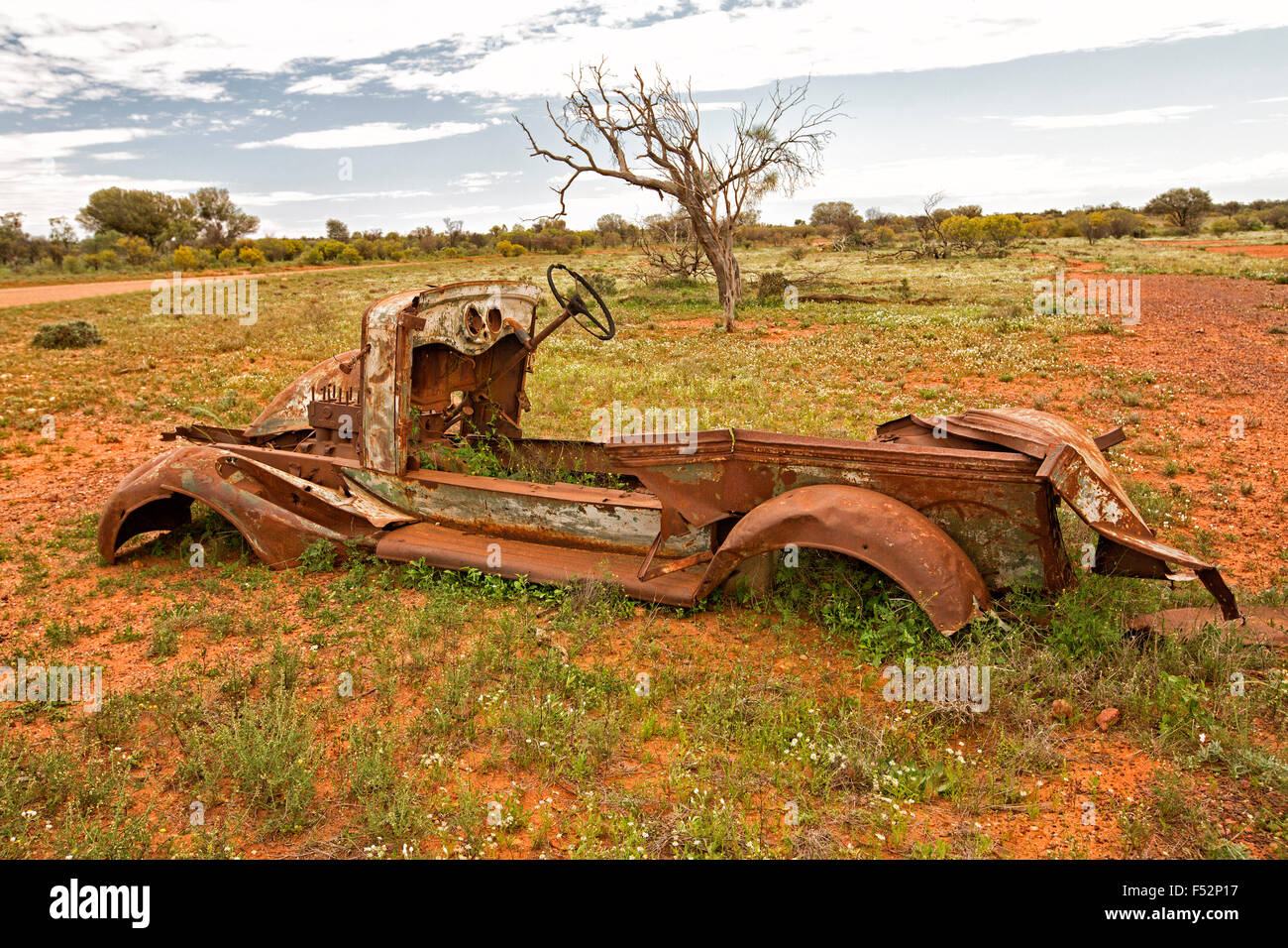 Reste der alten Nutzfahrzeug verrostet und verzichtet auf rotem australischen Outback Ebenen sommersprossige mit niedriger Vegetation nach Regenfällen Stockfoto