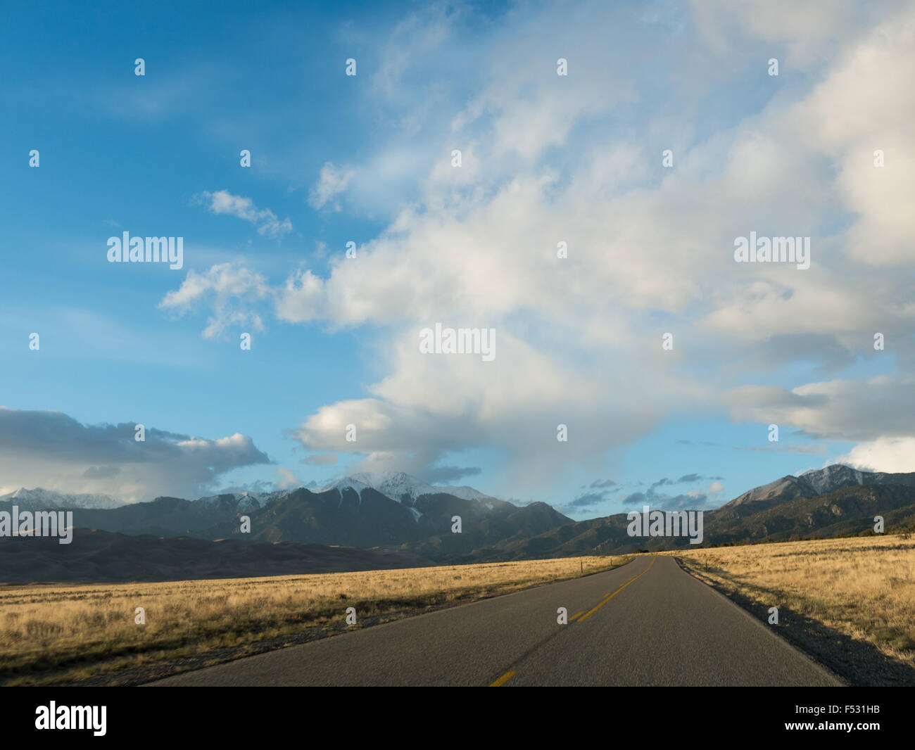 Landschaftsfoto zeigt Autobahn bis Sanddünen mit Bergen im Hintergrund Stockfoto