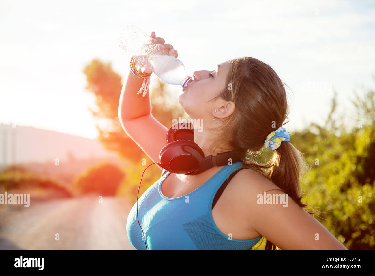 Schöne Mädchen Jogger im freien Trinkwasser bei Sonnenuntergang Stockfoto