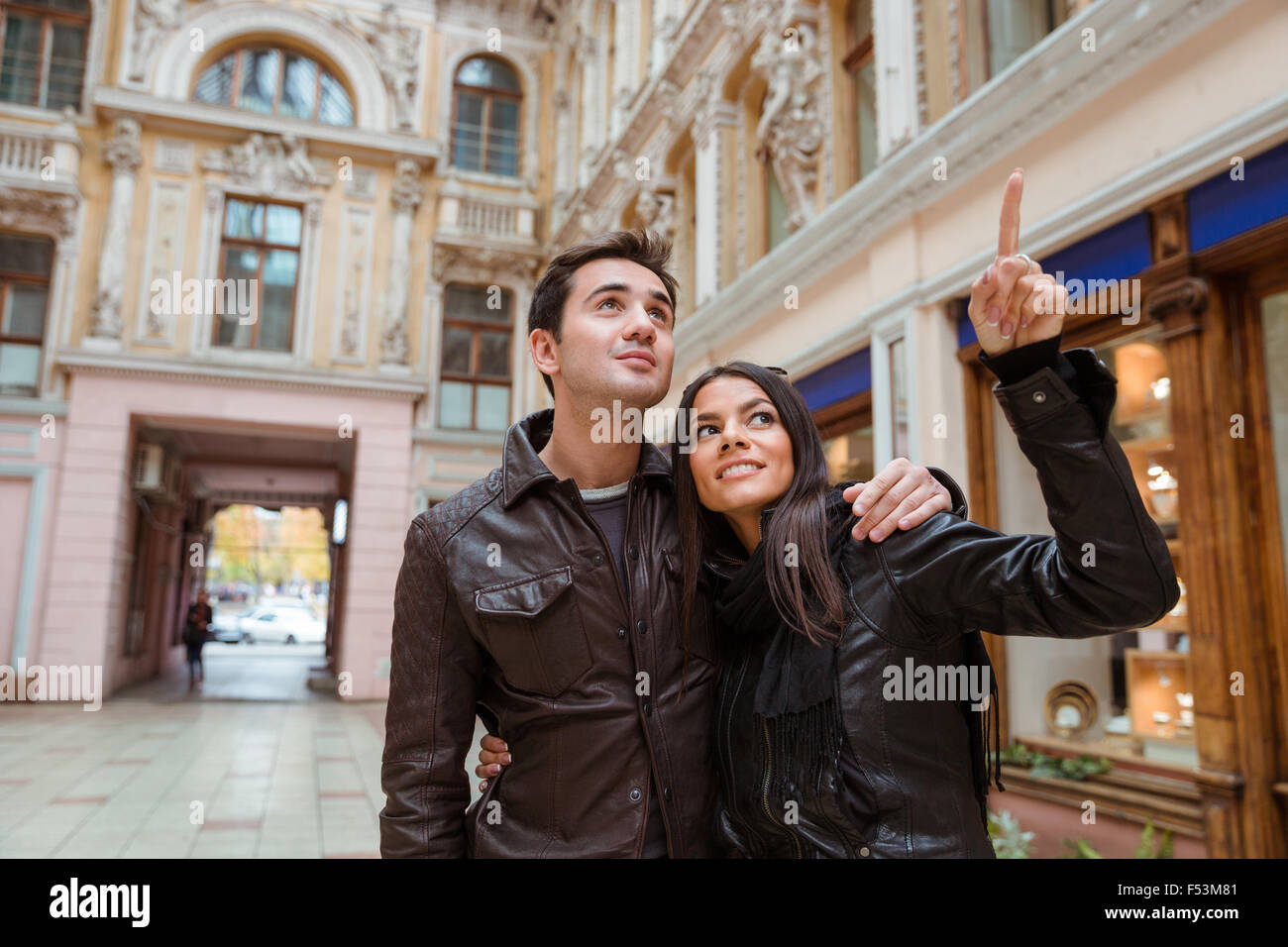 Porträt einer lächelnden Frau Zeigefinger auf etwas zu ihrem Freund draußen im alten europäischen Stadt Stockfoto